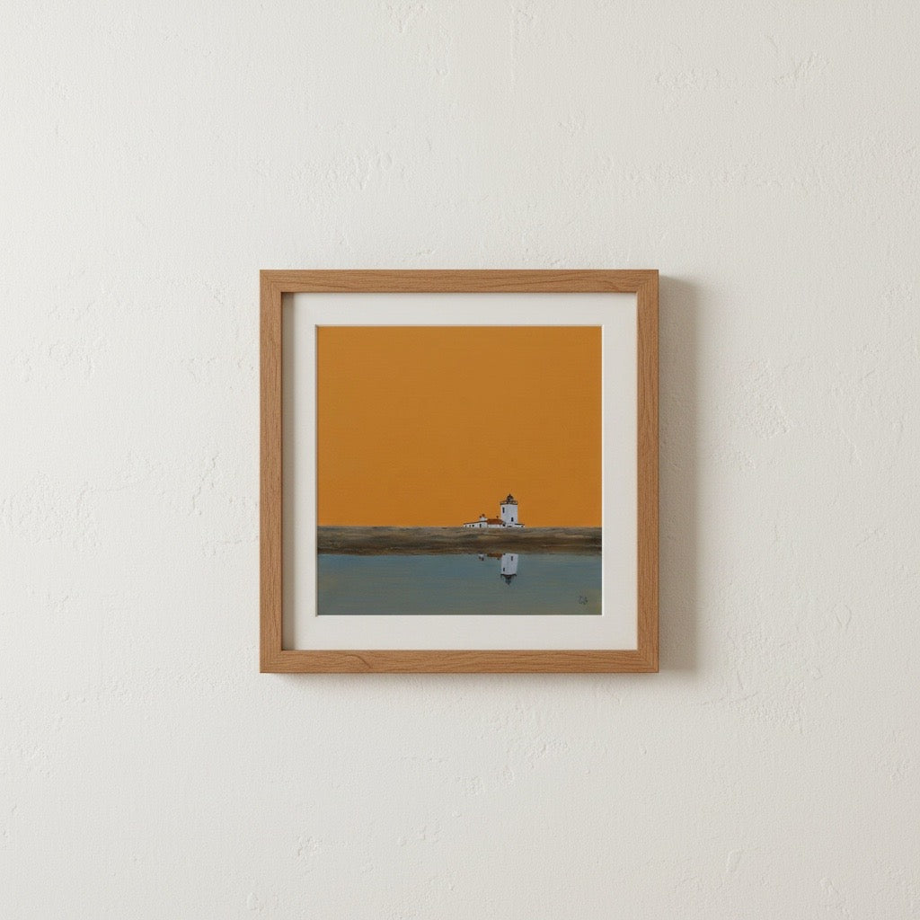 A framed art print featuring a minimalist landscape with a small lighthouse reflected in calm water under a solid orange sky, mounted on a white wall.