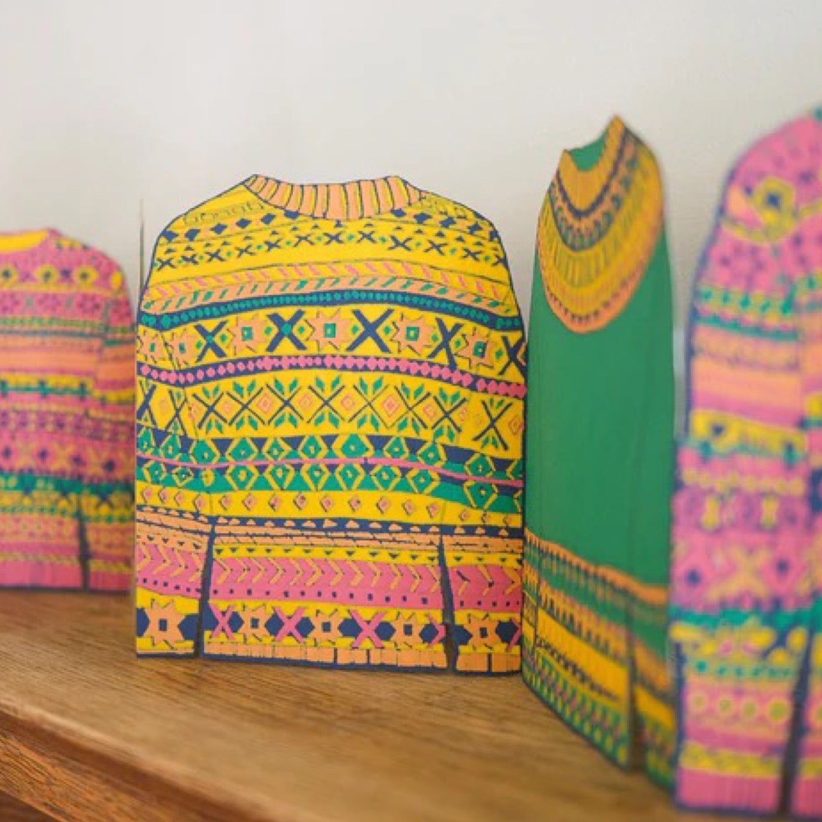 Colourful patterned sweaters garland on a wooden surface.