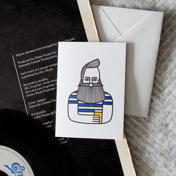 Card with a stylised illustration of a bearded man holding a pint on a white background, next to an envelope and album cover.