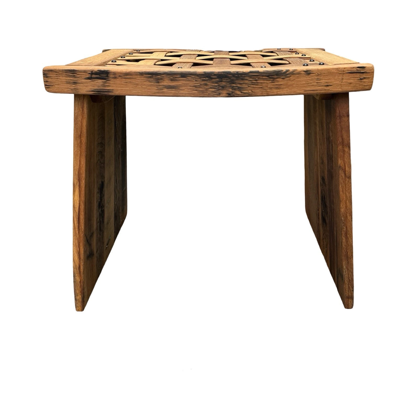 The side of a wooden table with two solid panel legs and a woven lattice wooden top.