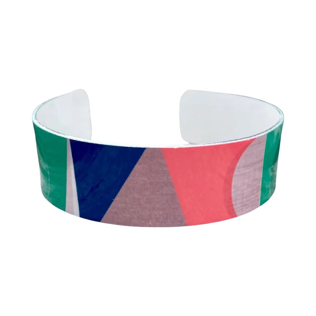 Front of narrow statement cuff bracelet featuring a cream and grey background and a red, green and blue abstract design.