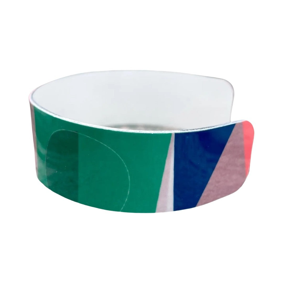 Side of narrow statement cuff bracelet featuring a cream and grey background and a red, green and blue abstract design.