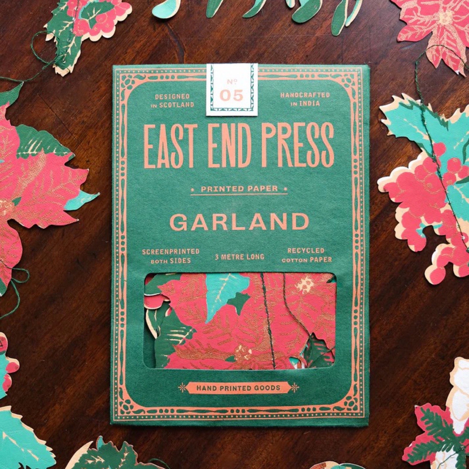 Packaging of East End Press Garland on a wooden surface with floral decorations.