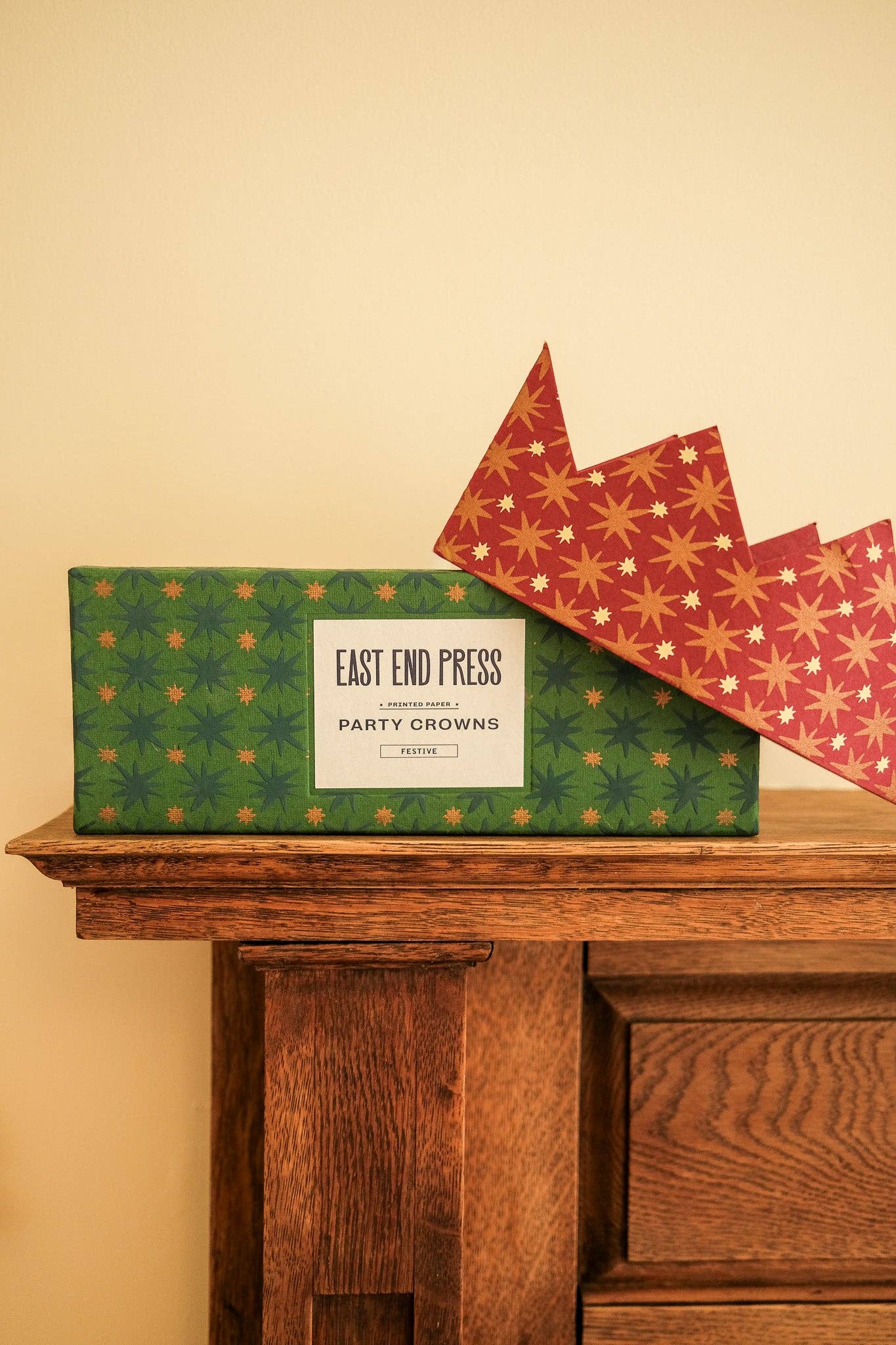 Green box with 'East End Press' label on a wooden surface against a beige wall.