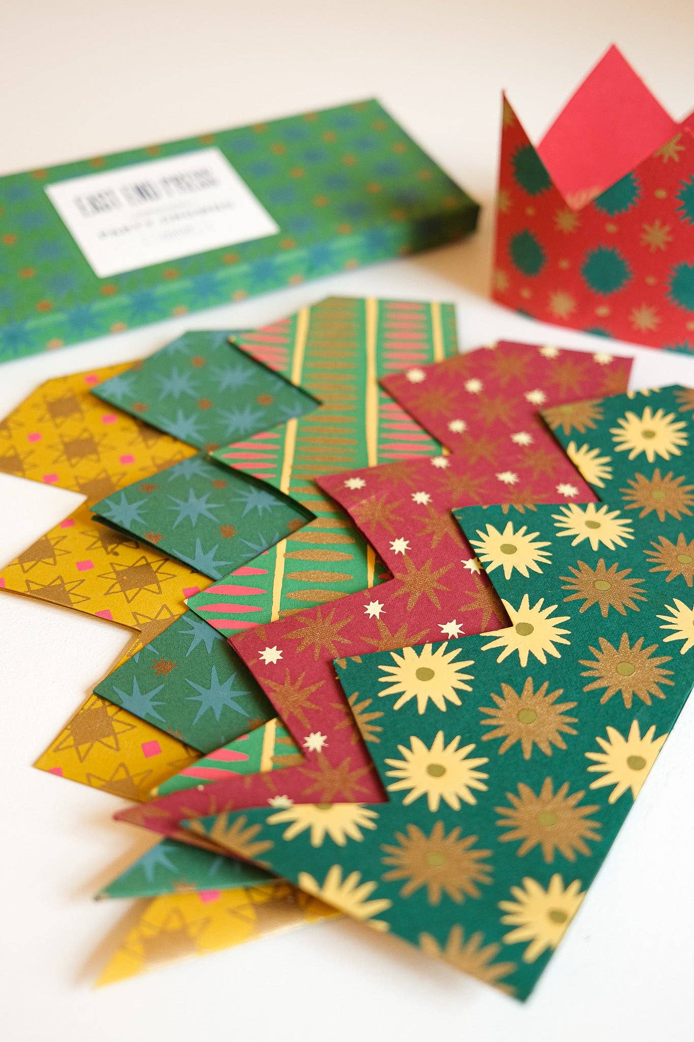 Colourful patterned paper crowns on a white surface with box in the background.