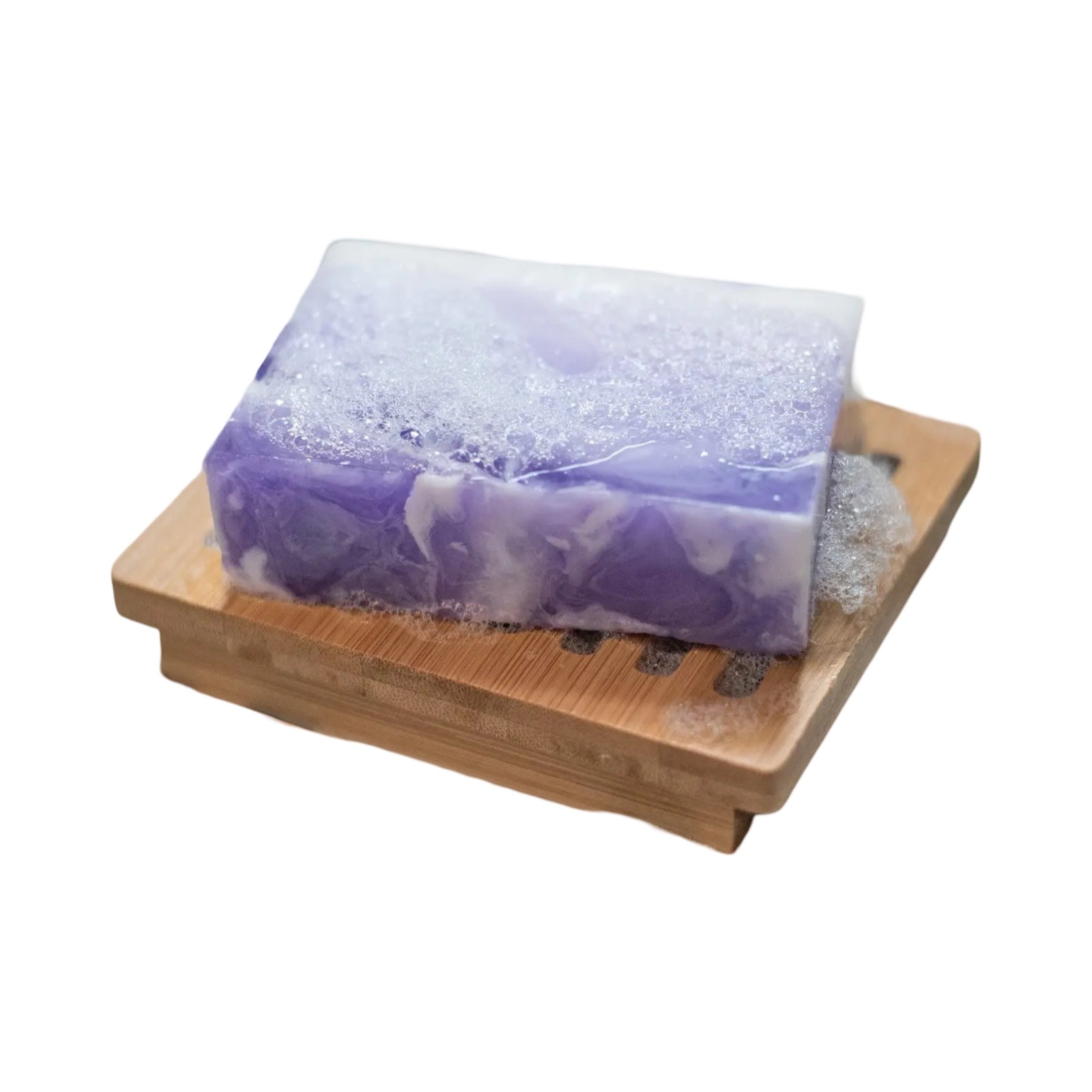 A bar of purple and white fig and cassis soap sitting on a wooden soap dish.