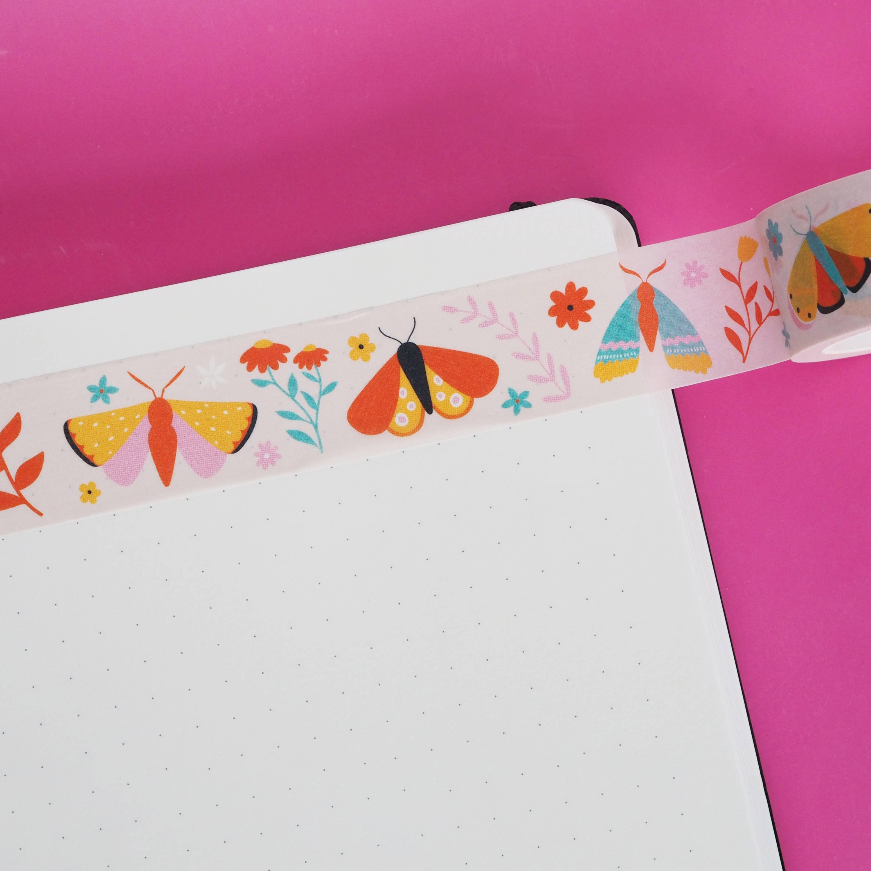 Decorative ribbon with butterfly design on a notebook against a pink background.