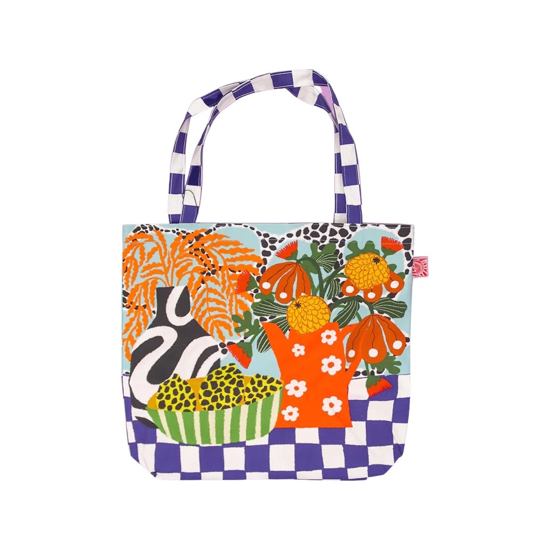 A fabulous, bright and colourful flower market tote bag featuring a black and white vase with orange leaves, a red jug with white daisies full of colourful flowers and a blue and white checked base.