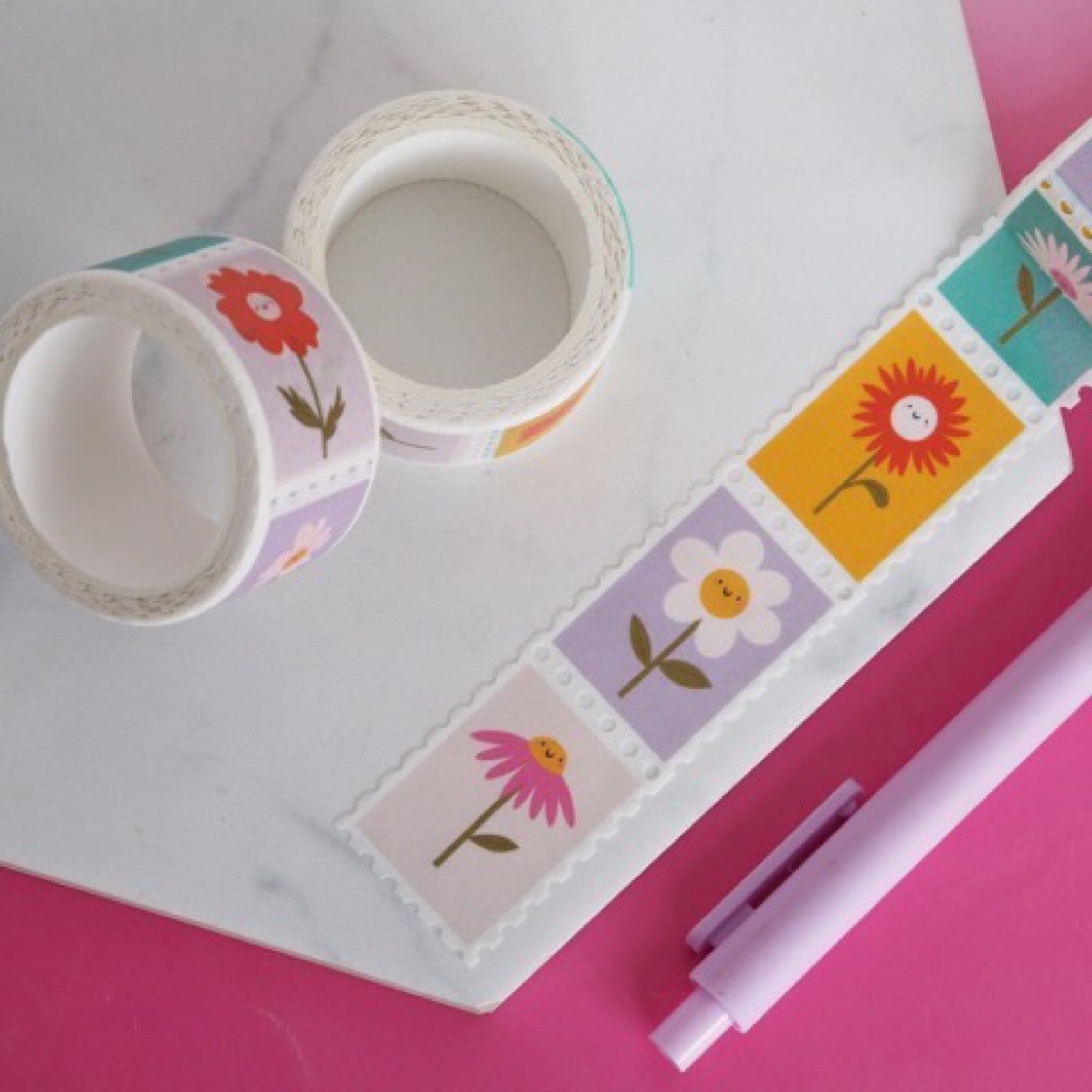 Rolls of washi tape with colourful flowers in the design of stamps on a table.