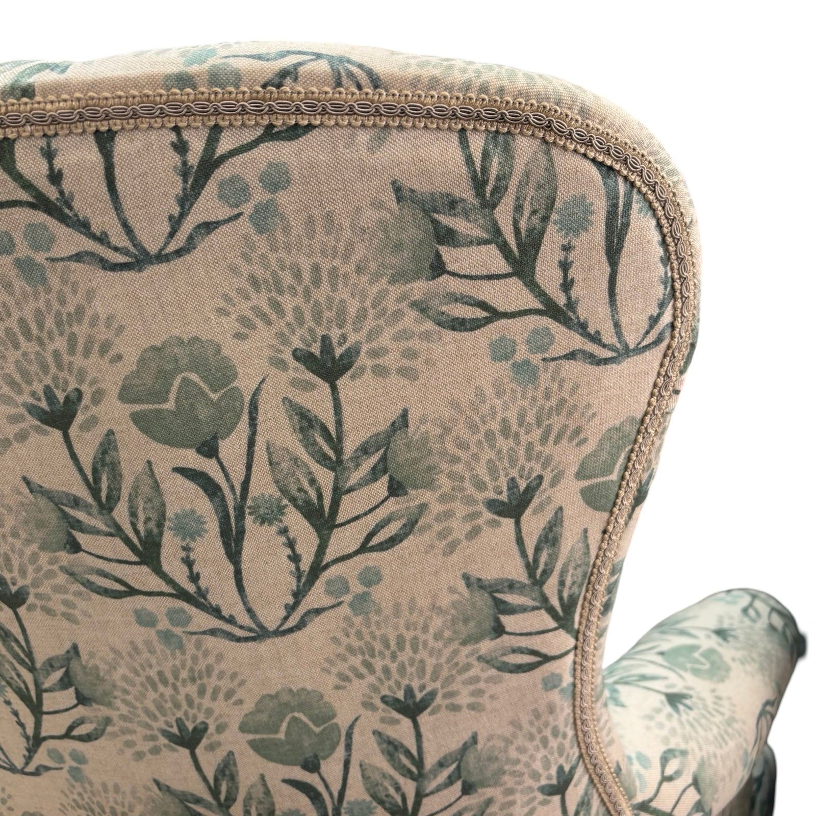 The back binding deatil of an occasional armchair in cream linen fabric with flowers in soft blues and greens.