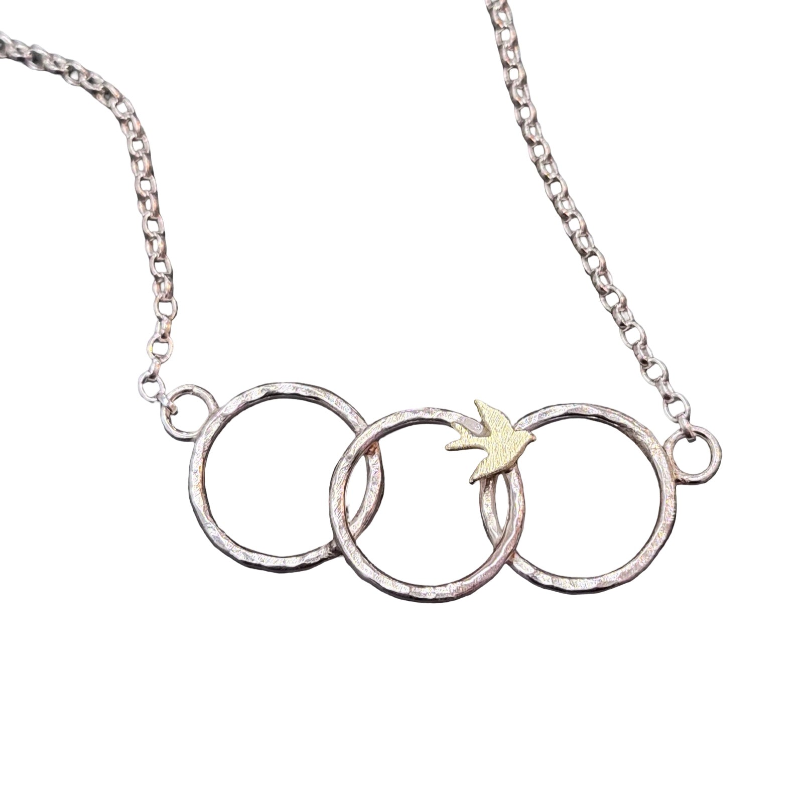 Silver necklace with three interlocking rings and a small yellow bird on a white background.