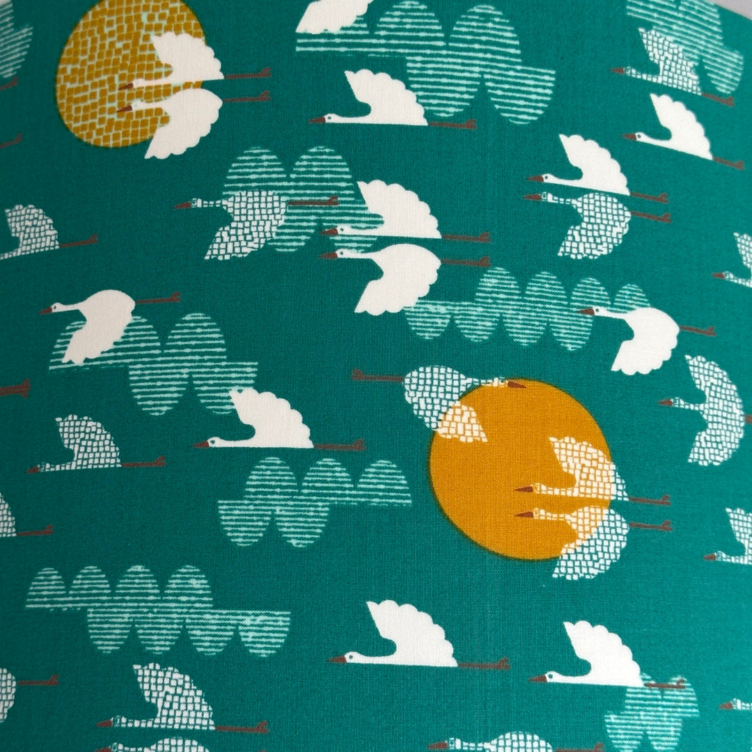 Green fabric with white flying birds and mustard moons