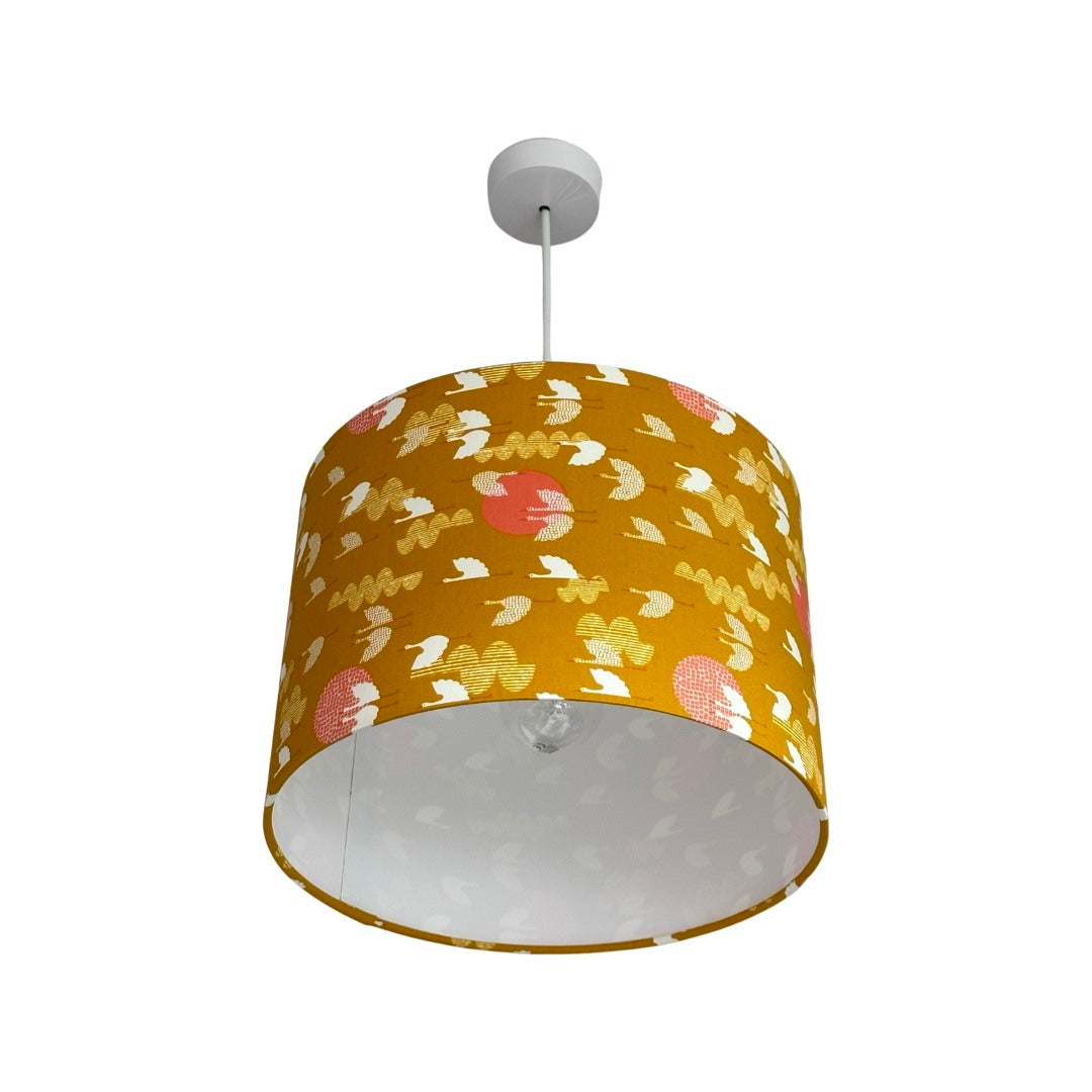 Drum lampshade covered in mustard cotton fabric with white birds and pink moons