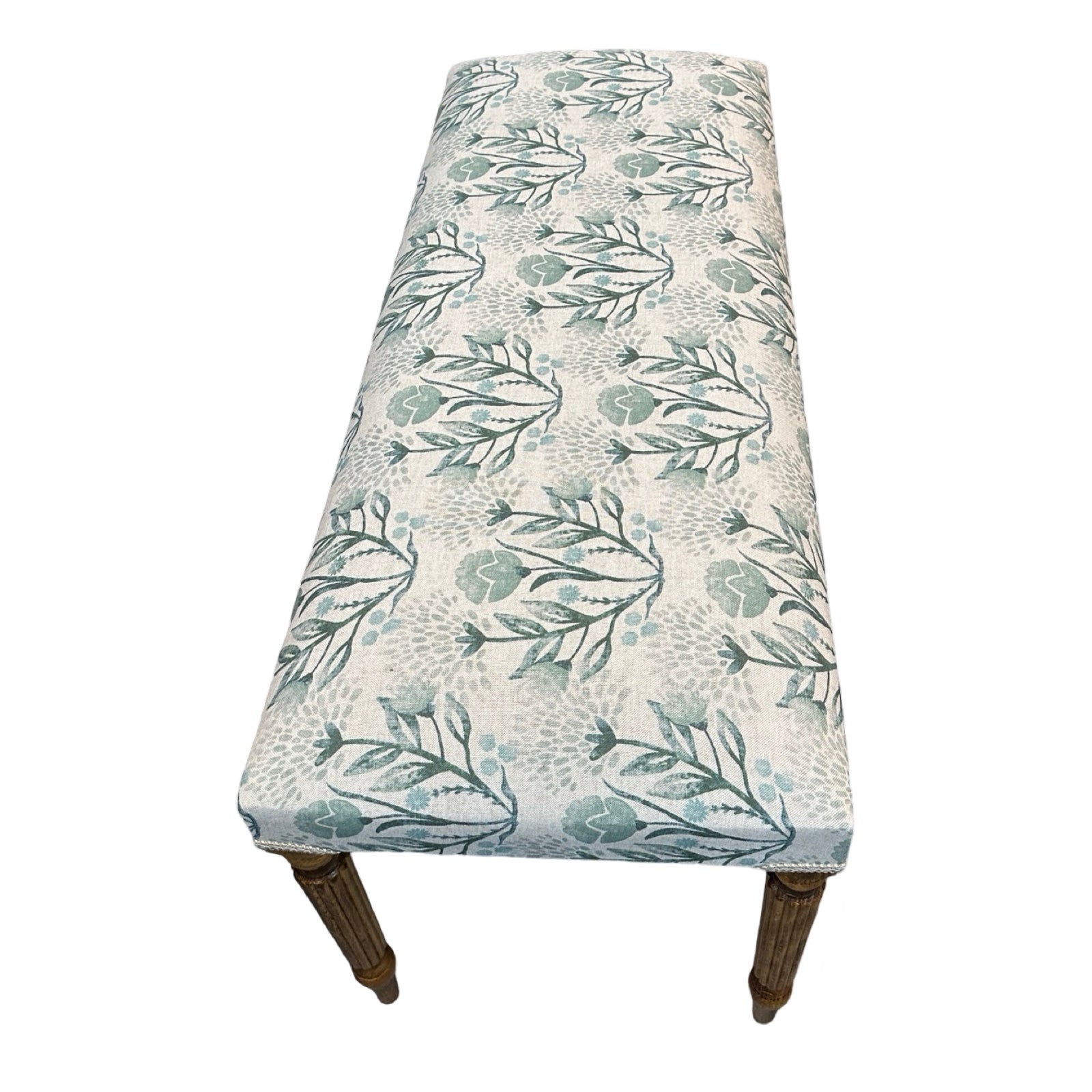 The end of a rectangular bench covered in cream linen fabric with flowers in soft blues and greens and finished with cream binding and mahogany legs.