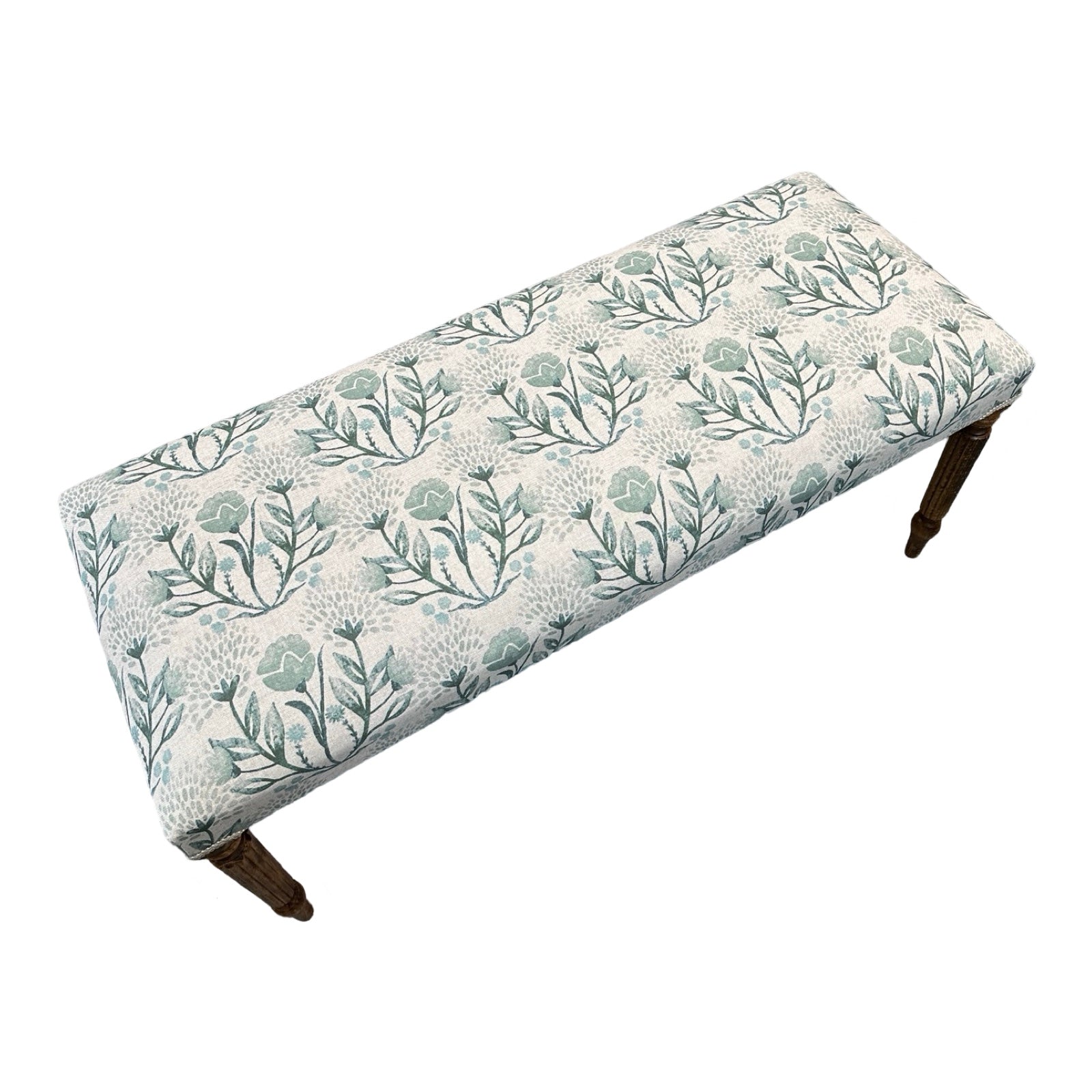 The top of a rectangular bench covered in cream linen fabric with flowers in soft blues and greens and finished with cream binding and mahogany legs.