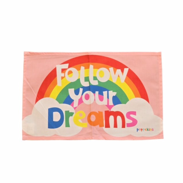 Colourful fabric placemats featuring a rainbow with clouds at each end and the text 'Follow Your Dreams' in multicoloured lettering against a pink background.