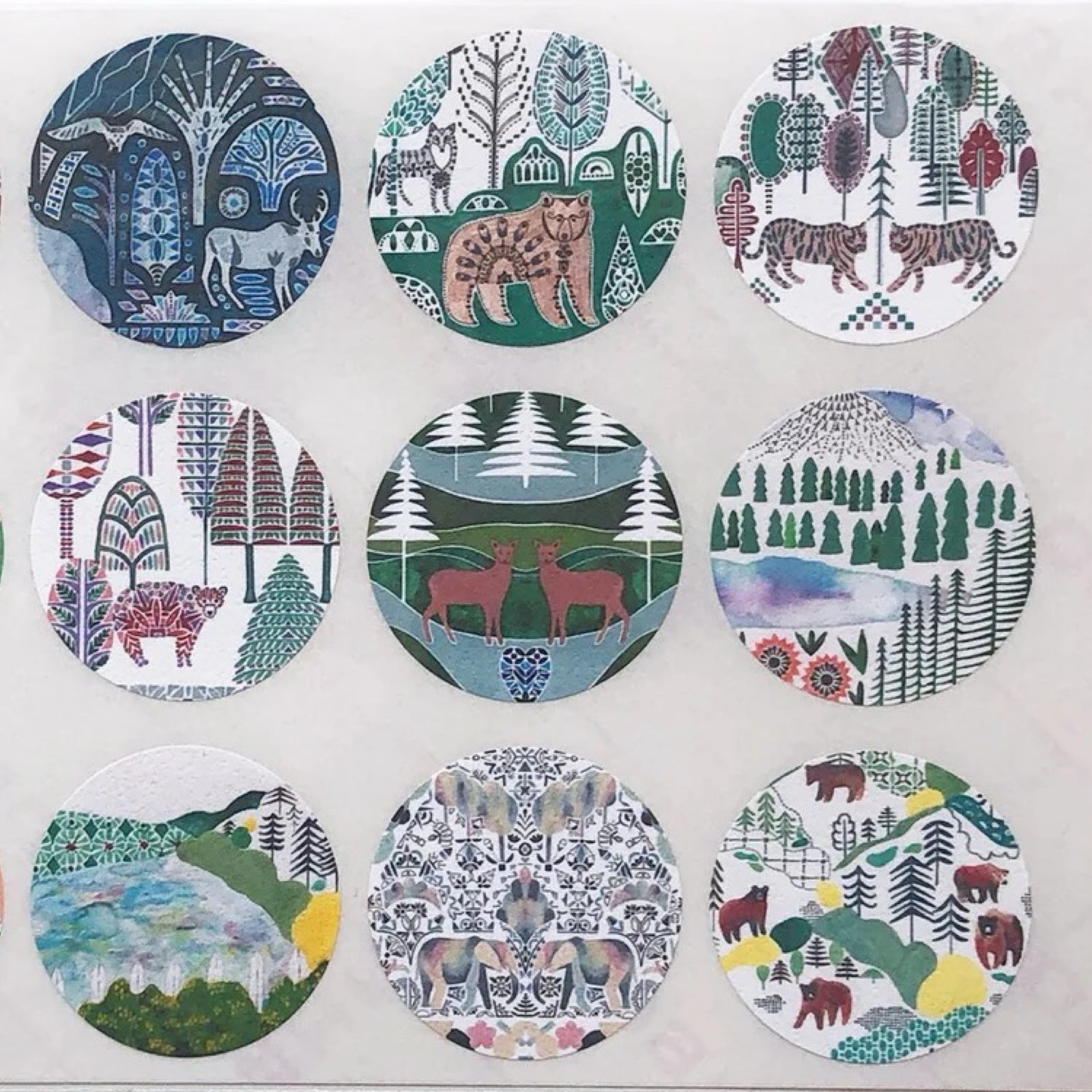 Set of round stickers with nature-themed designs featuring animals and landscapes.