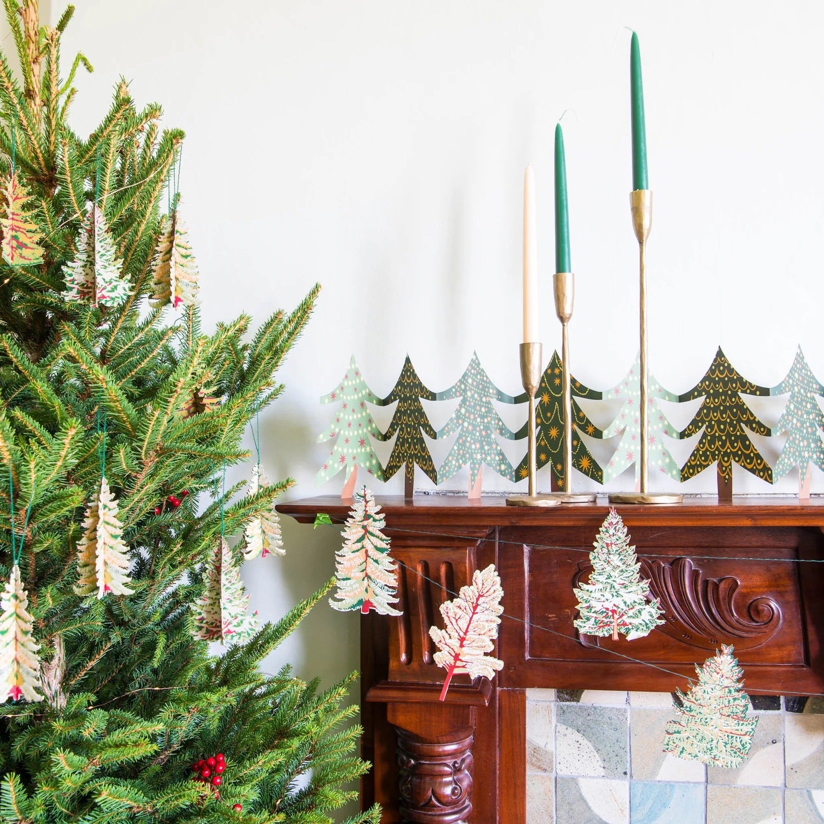 Decorative Christmas trees on a mantelpiece with a lit candle.