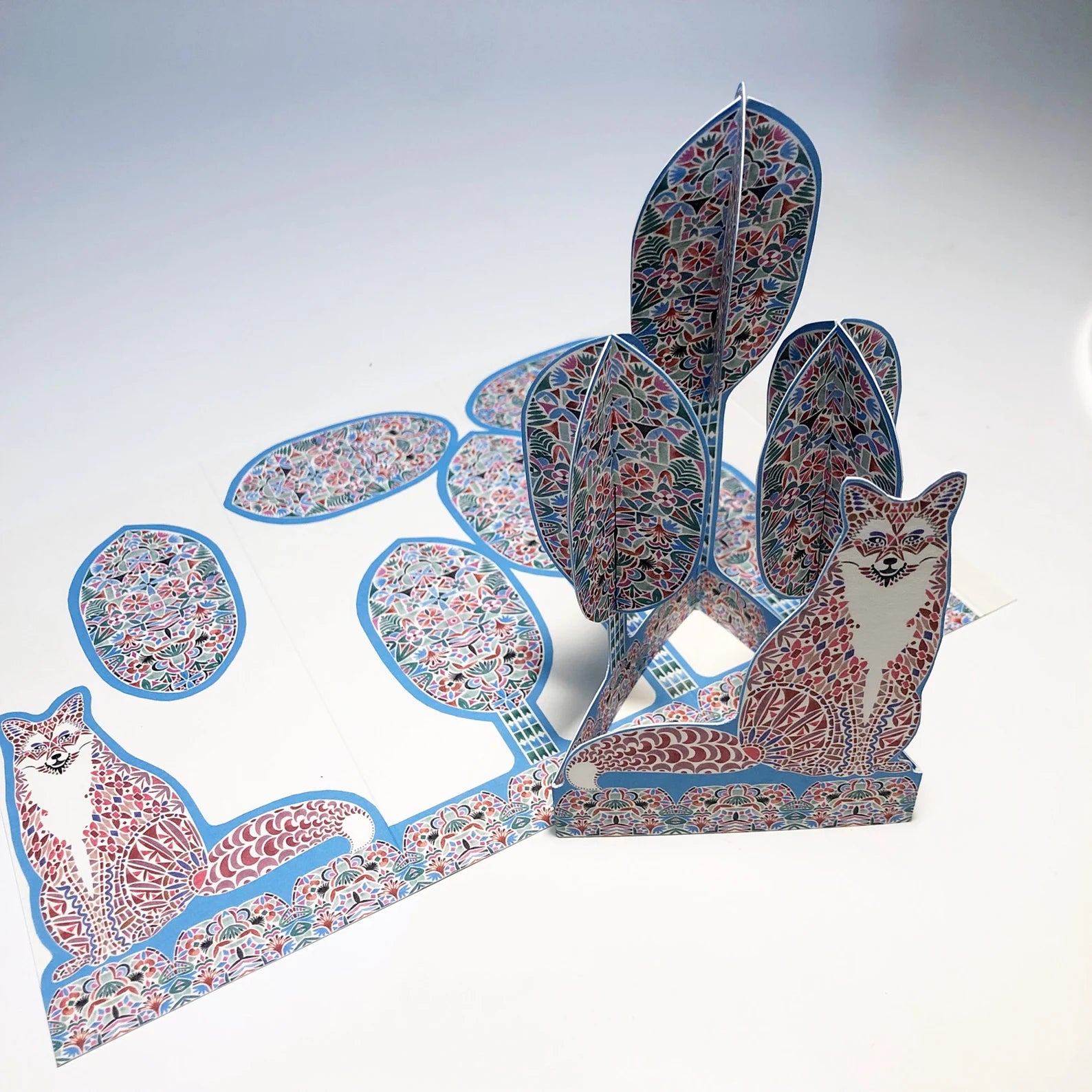 Decorative paper sculpture of a fox with floral patterns on a white background.