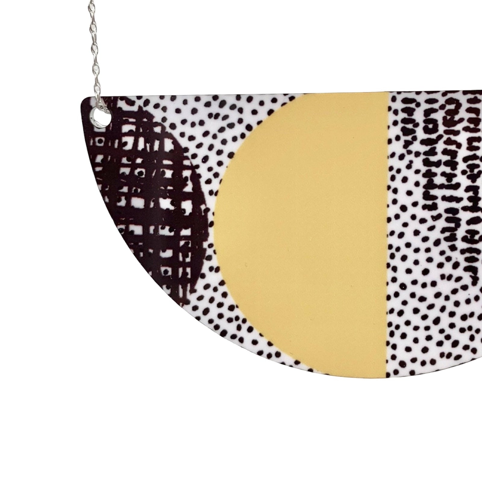 Half-circle pendant with black and white pattern and gold center on a white background.