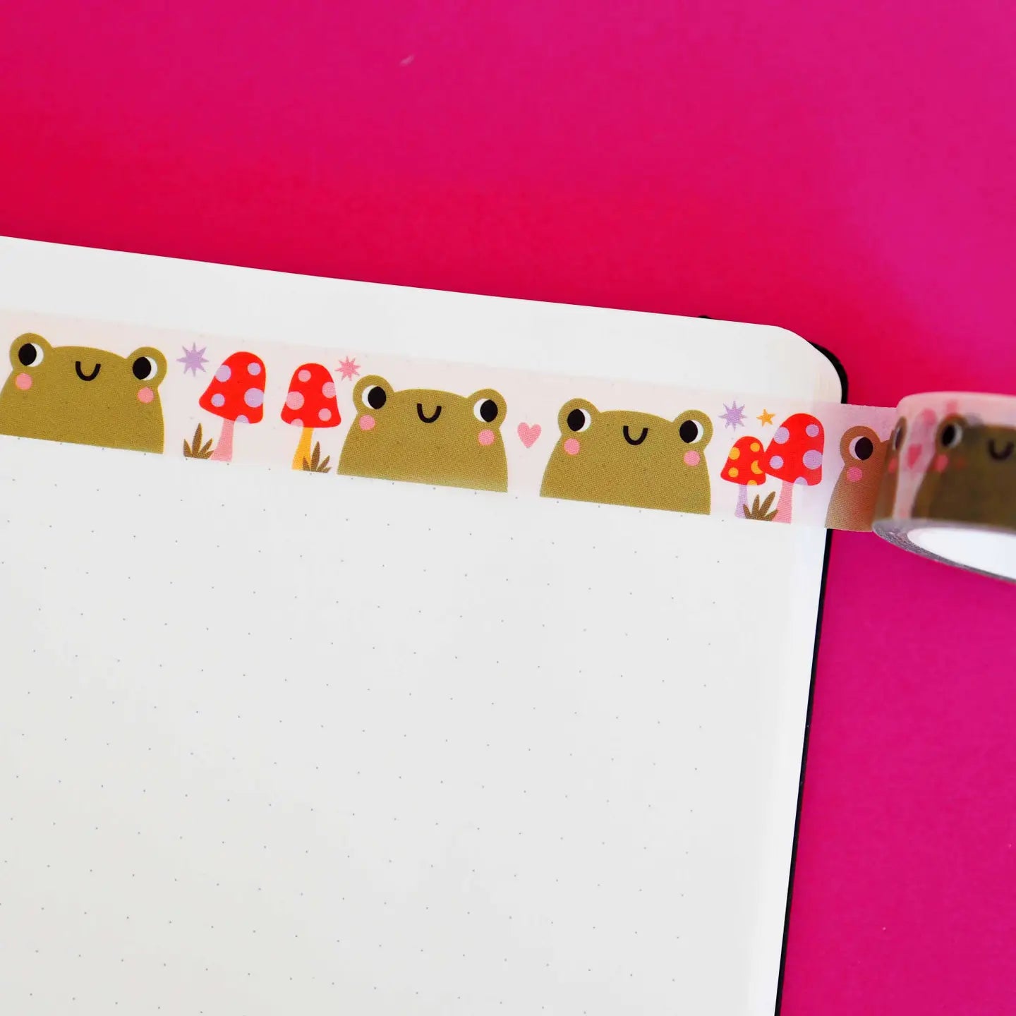 Decorative tape with cartoon frog and mushroom designs on a pink background.