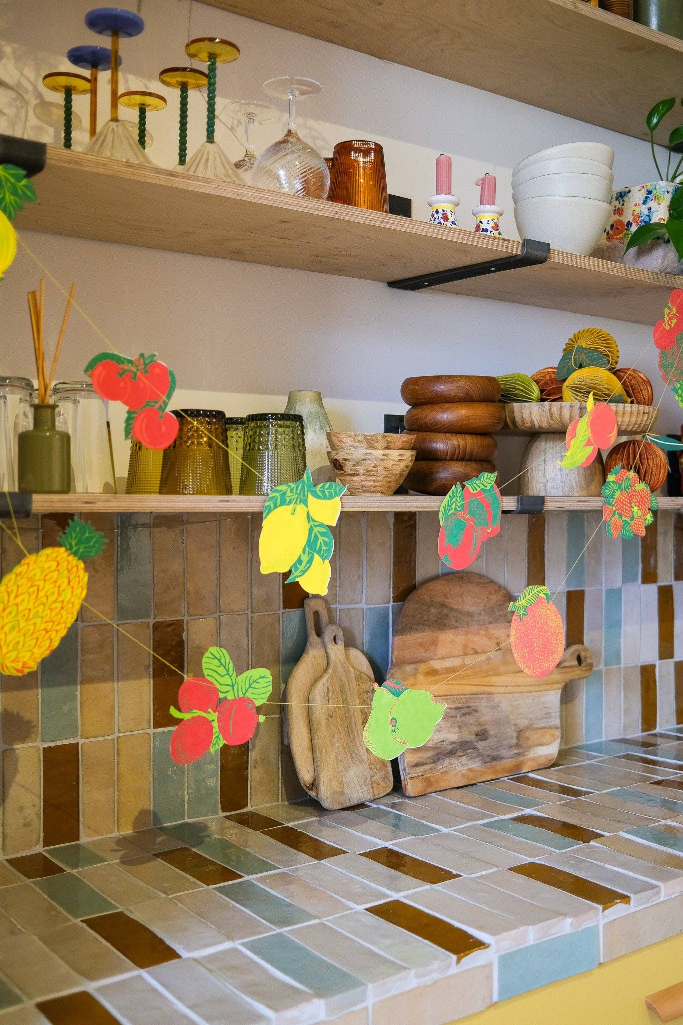 Kitchen shelves with various items including bowls, a cutting board, and decorative fruit garland.