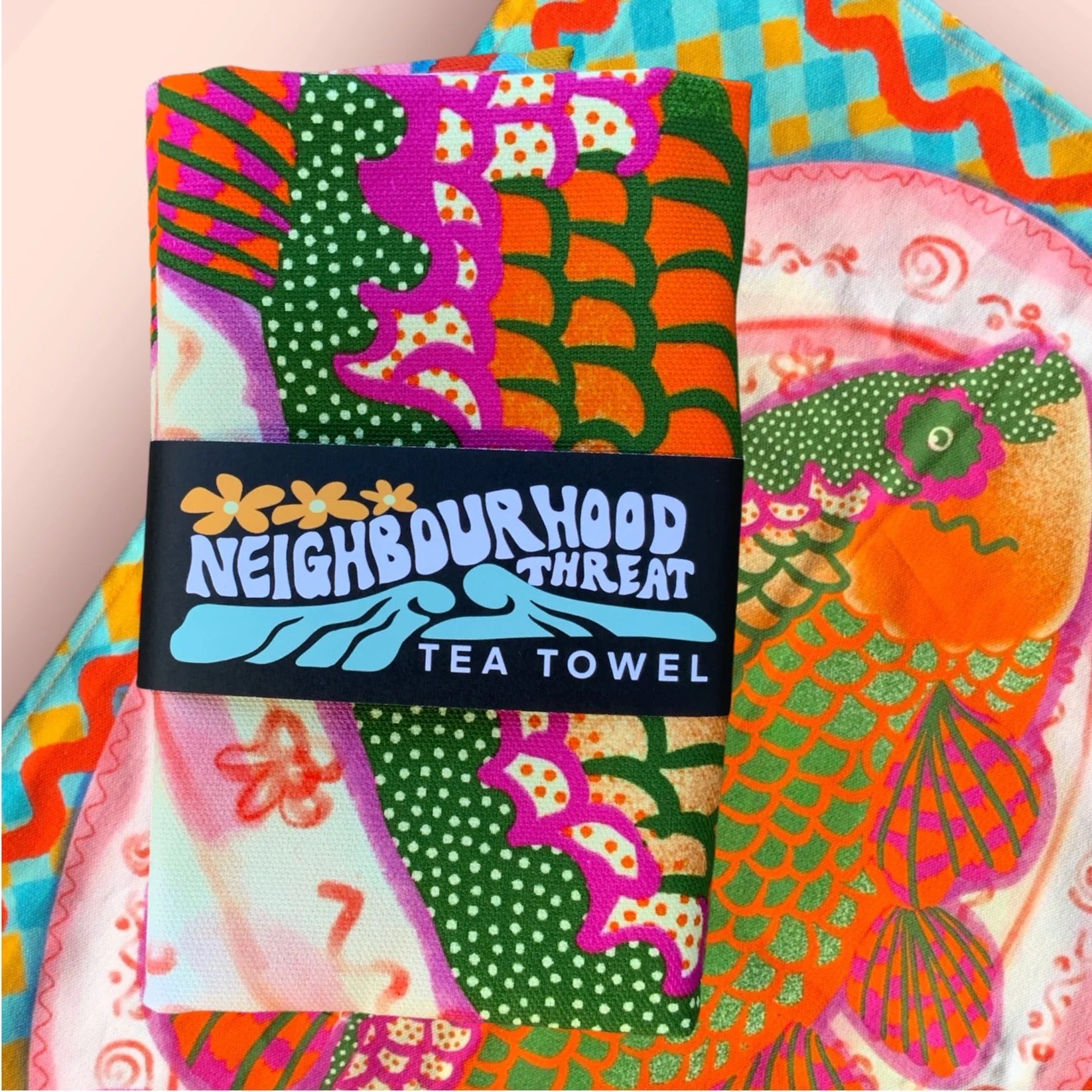 Colorful tea towel with 'Neighbourhood Threat' branding and vibrant patterns.