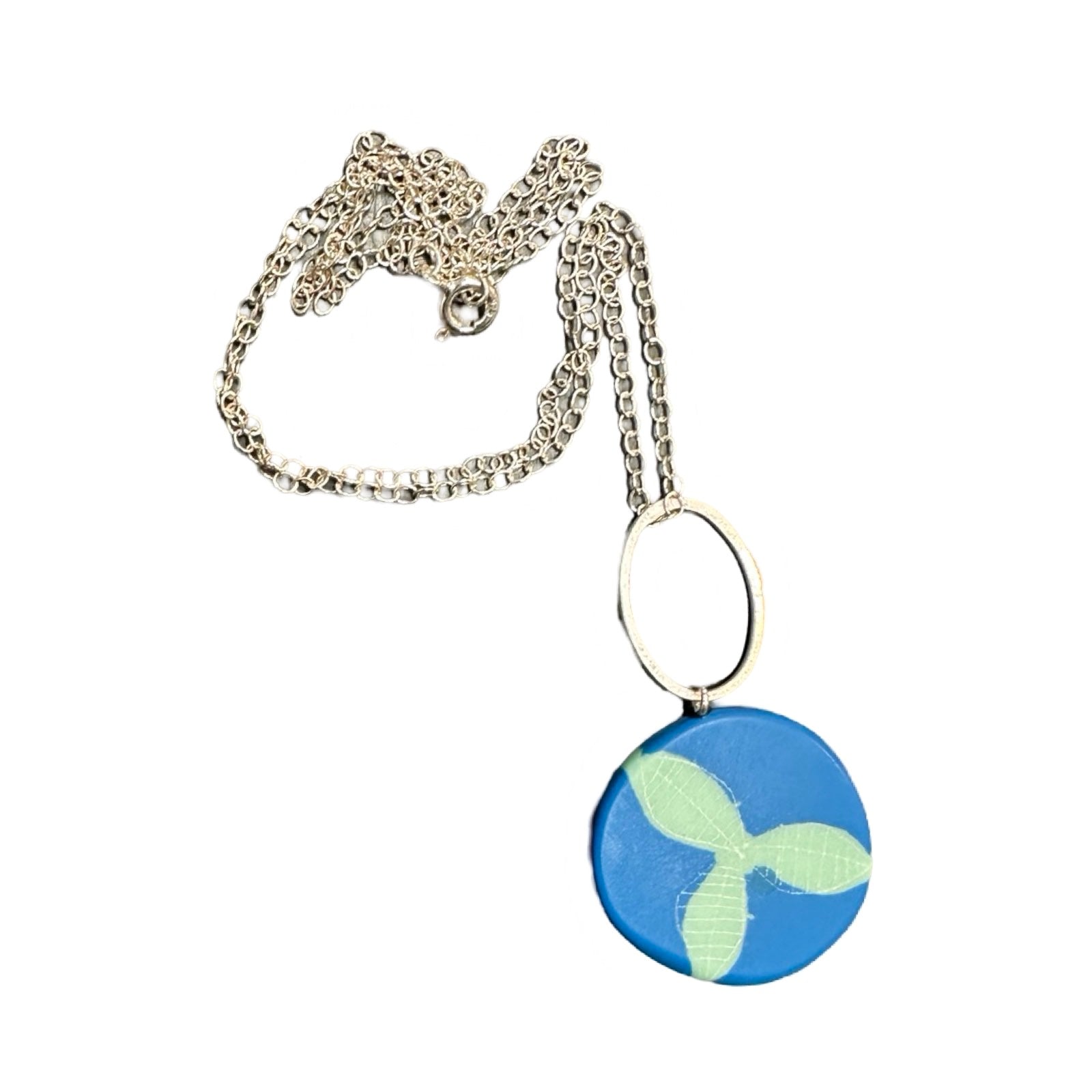 A blue pendant necklace made from resin with green leaves in the centre on a silver chain.