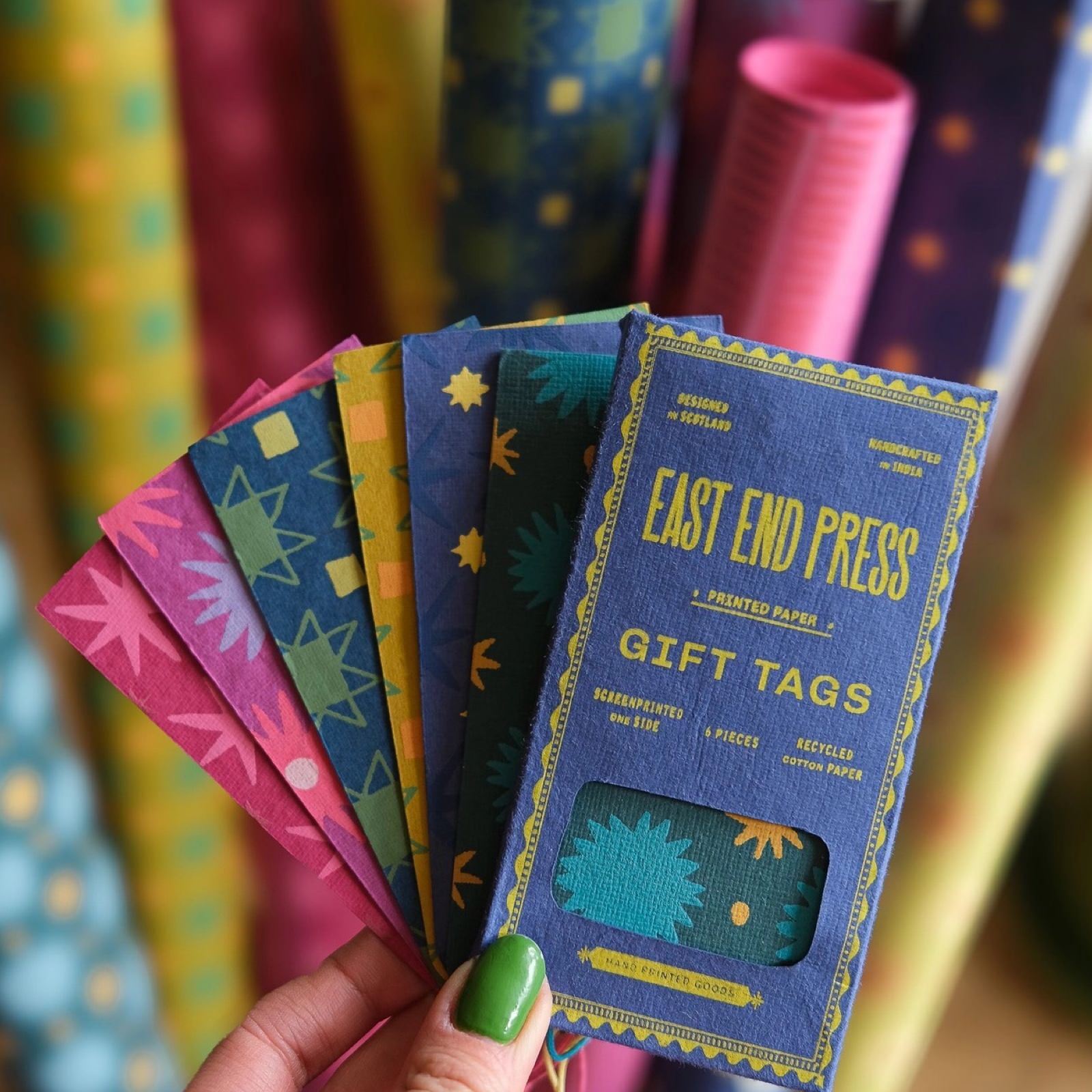 6 colourful gift tags with contrasting stars patterns with a blue rectangular paper packet.