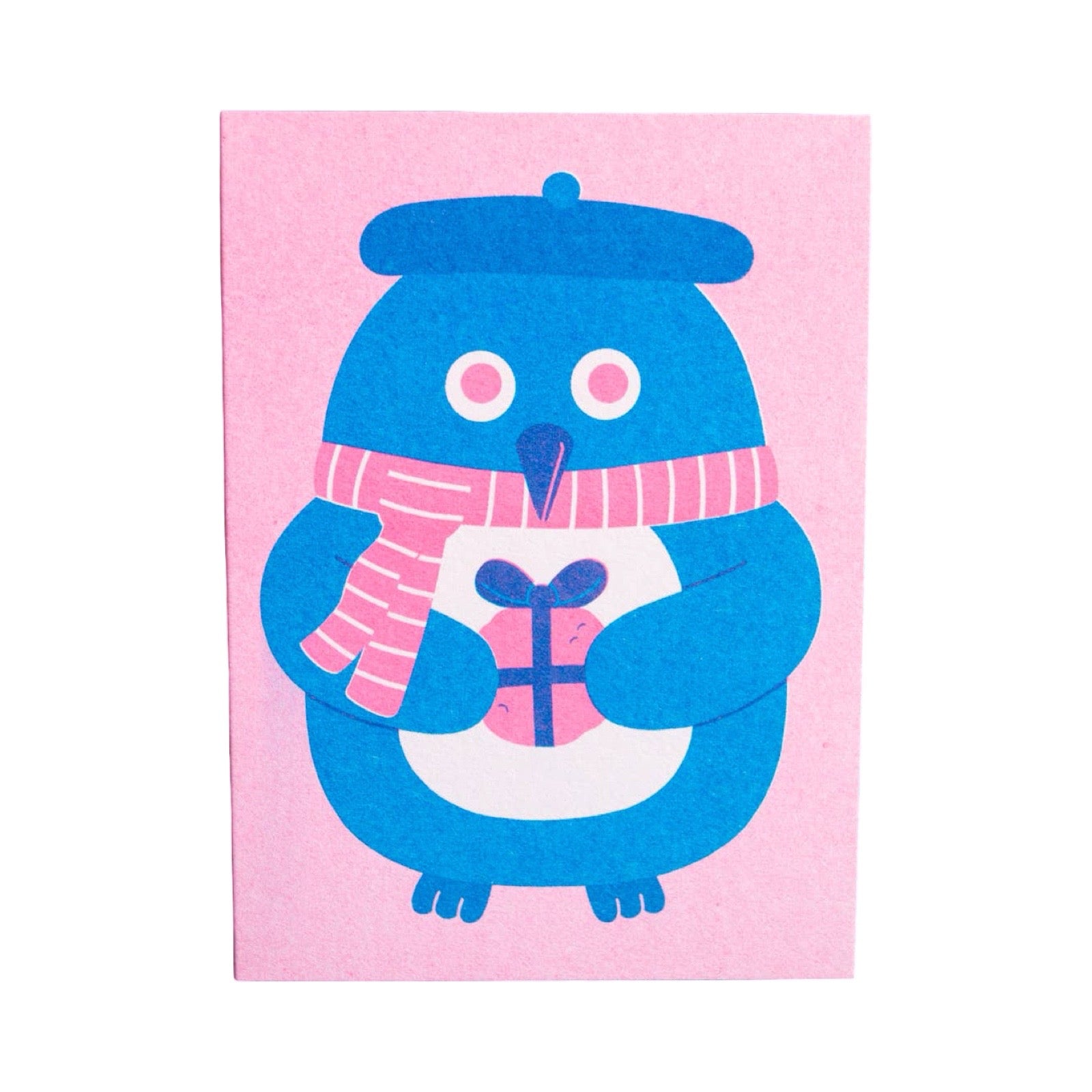 A greeting card featuring a blue penguin wearing a pink and white striped scarf and holding a pink gift, set against a light pink background.