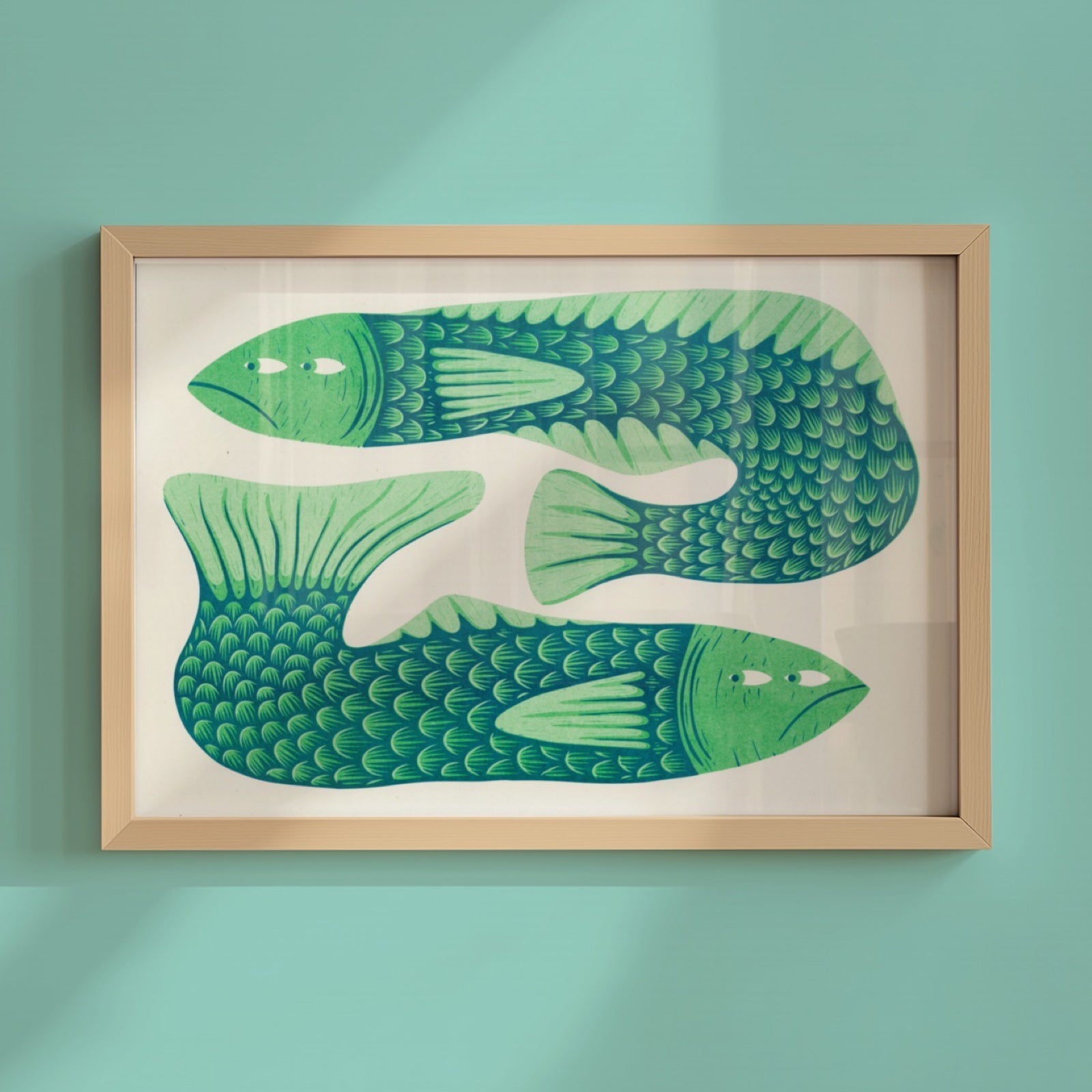 Framed artwork of two green fish on a light background.