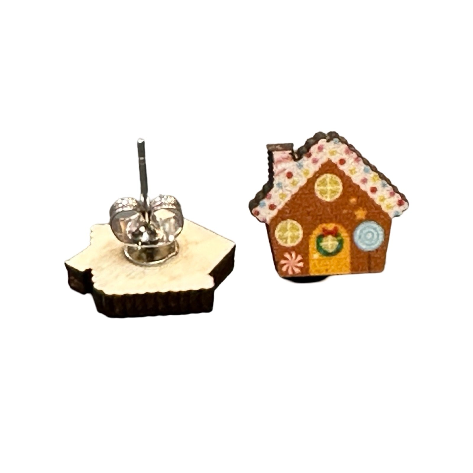 A pair of wooden stud earrings shaped like a gingerbread house with decorative house.
