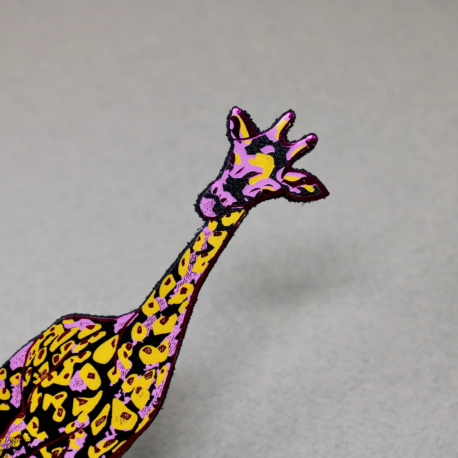 Colourful giraffe bookmark on a grey background.