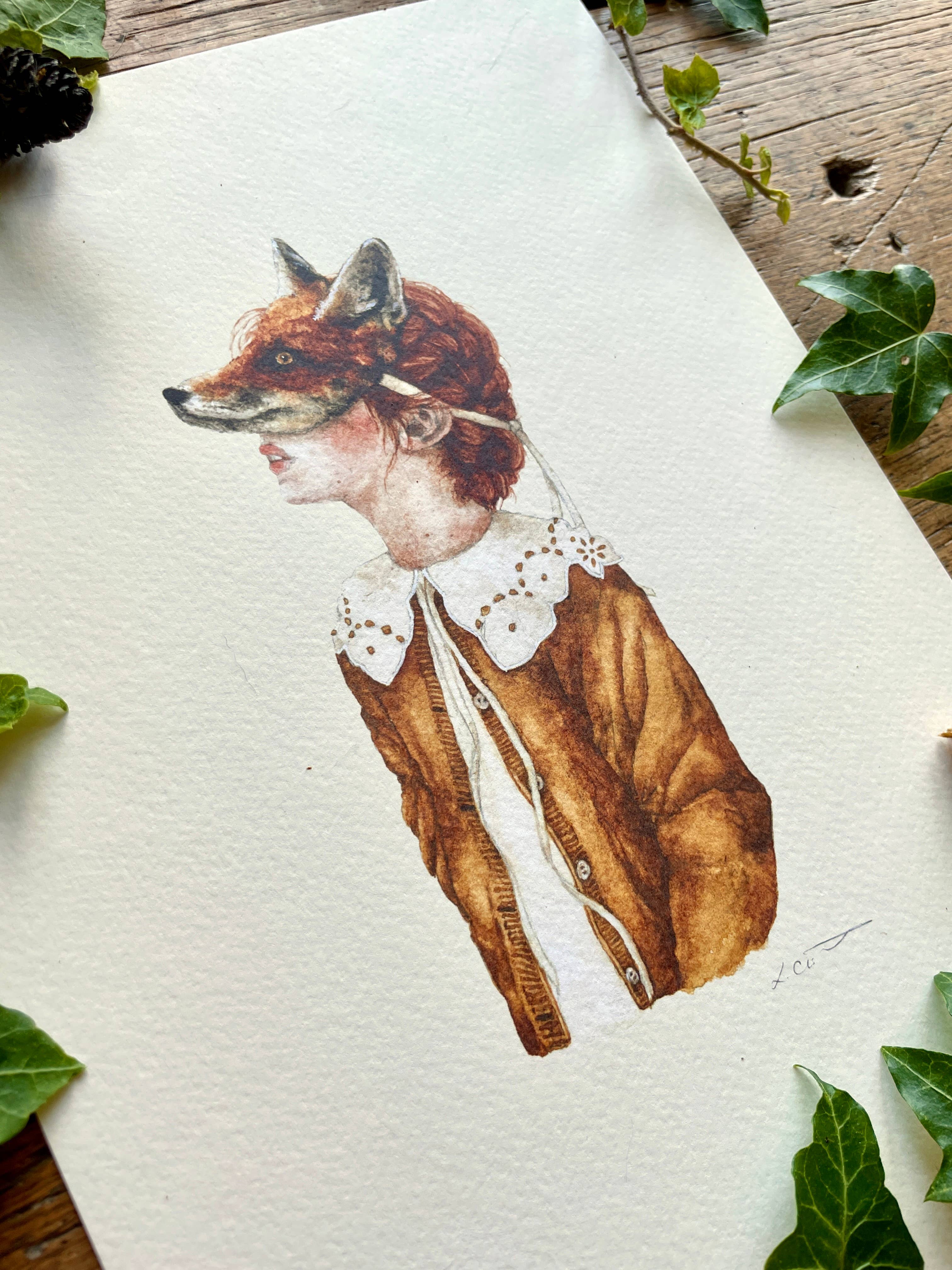 An art print of a girl wearing a fox mask, dressed in a white shirt with a fabulous lace collar and a brown coat, and surrounded by leaves and acorns.
