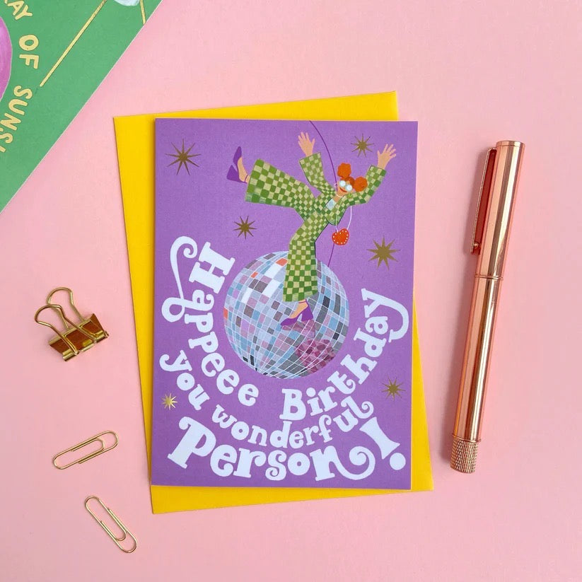 Birthday card with disco ball and text on a pink background with office supplies.