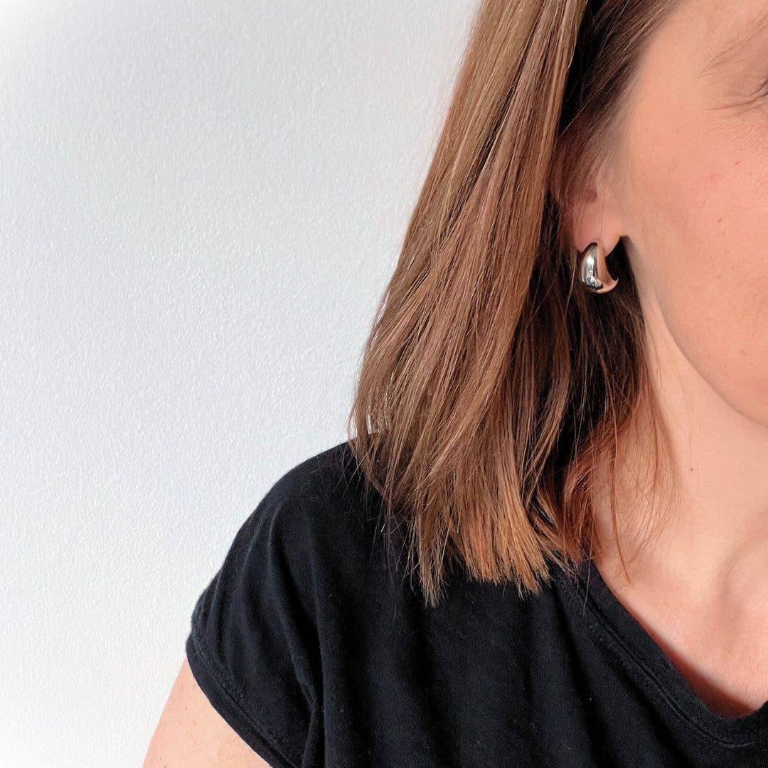 Close-up of a person wearing a silver earring with a white background.
