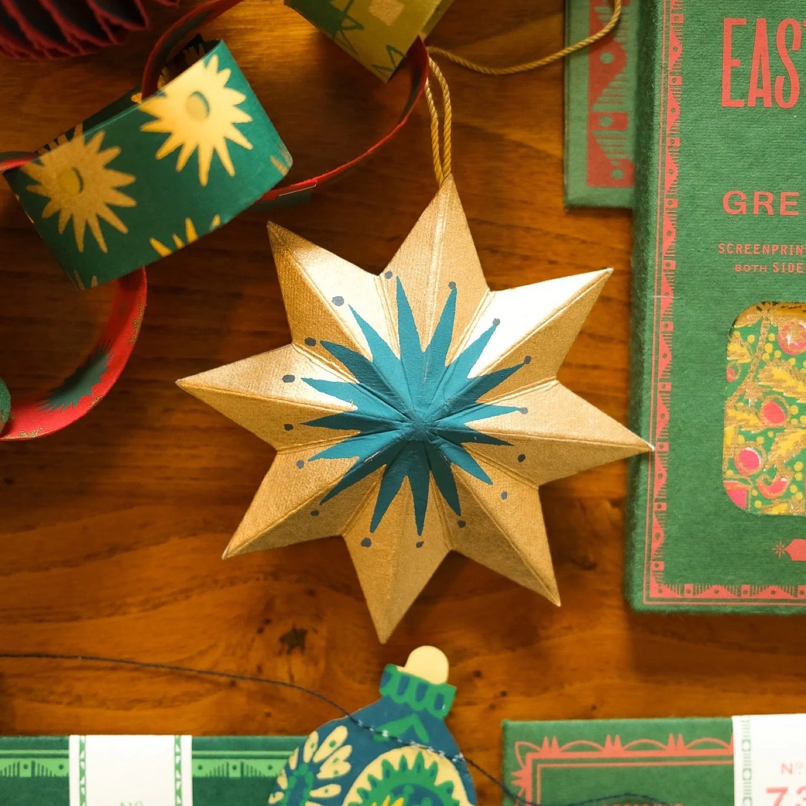 Star-shaped decorative ornament on a wooden surface with books and gift boxes.