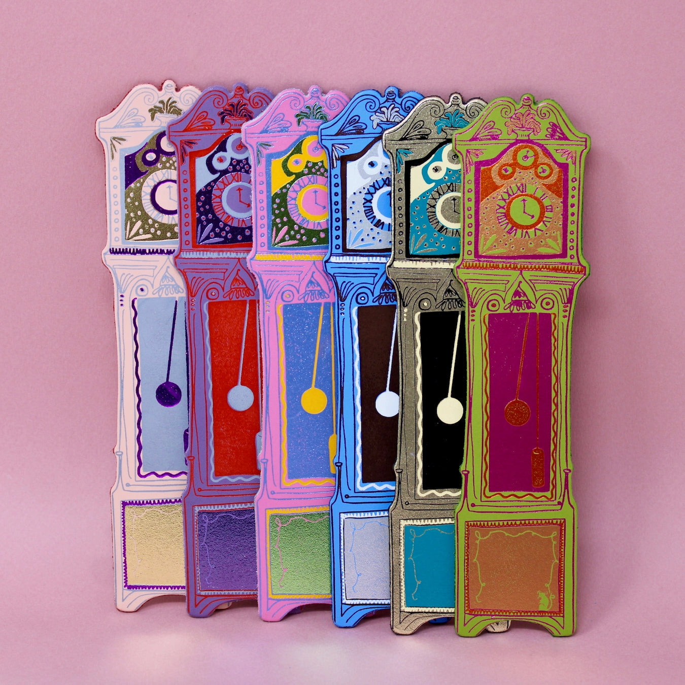 Colourful grandfather clock-shaped bookmarks on a pink background.