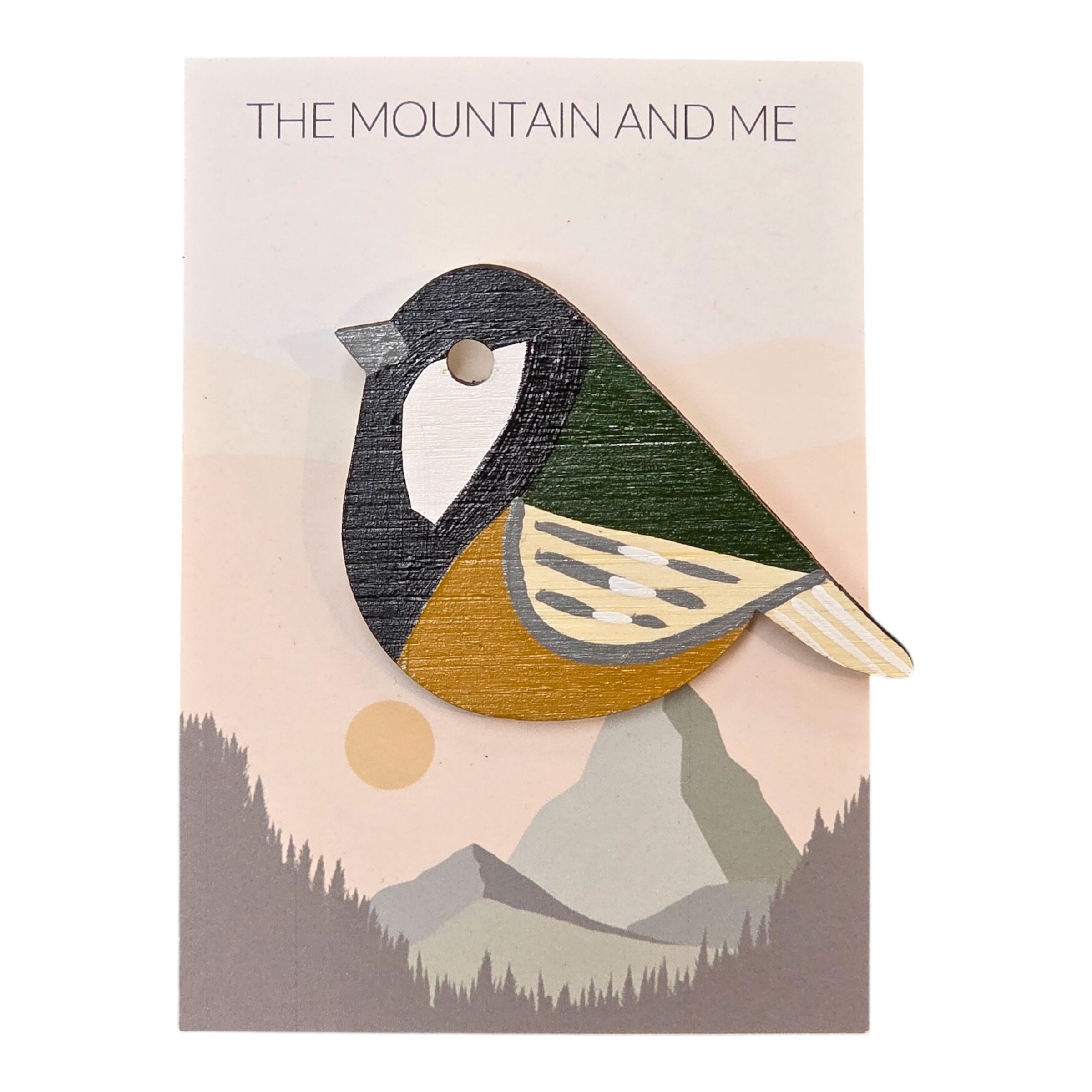 A bird-shaped great tit wooden brooch hand-painted in black, green, yellow and grey on a backing card.
