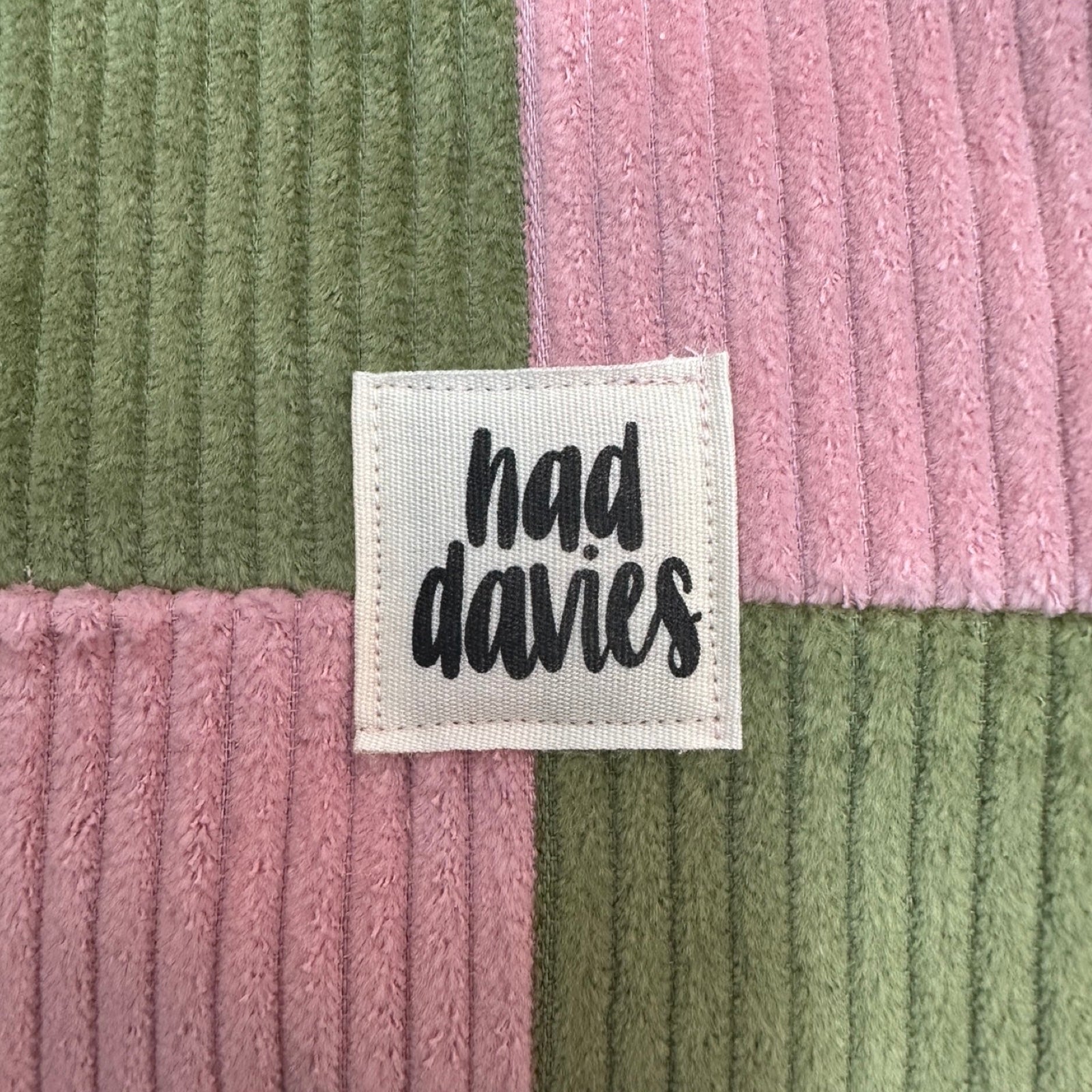 Textile with 'had davies' label on a green and pink striped background.