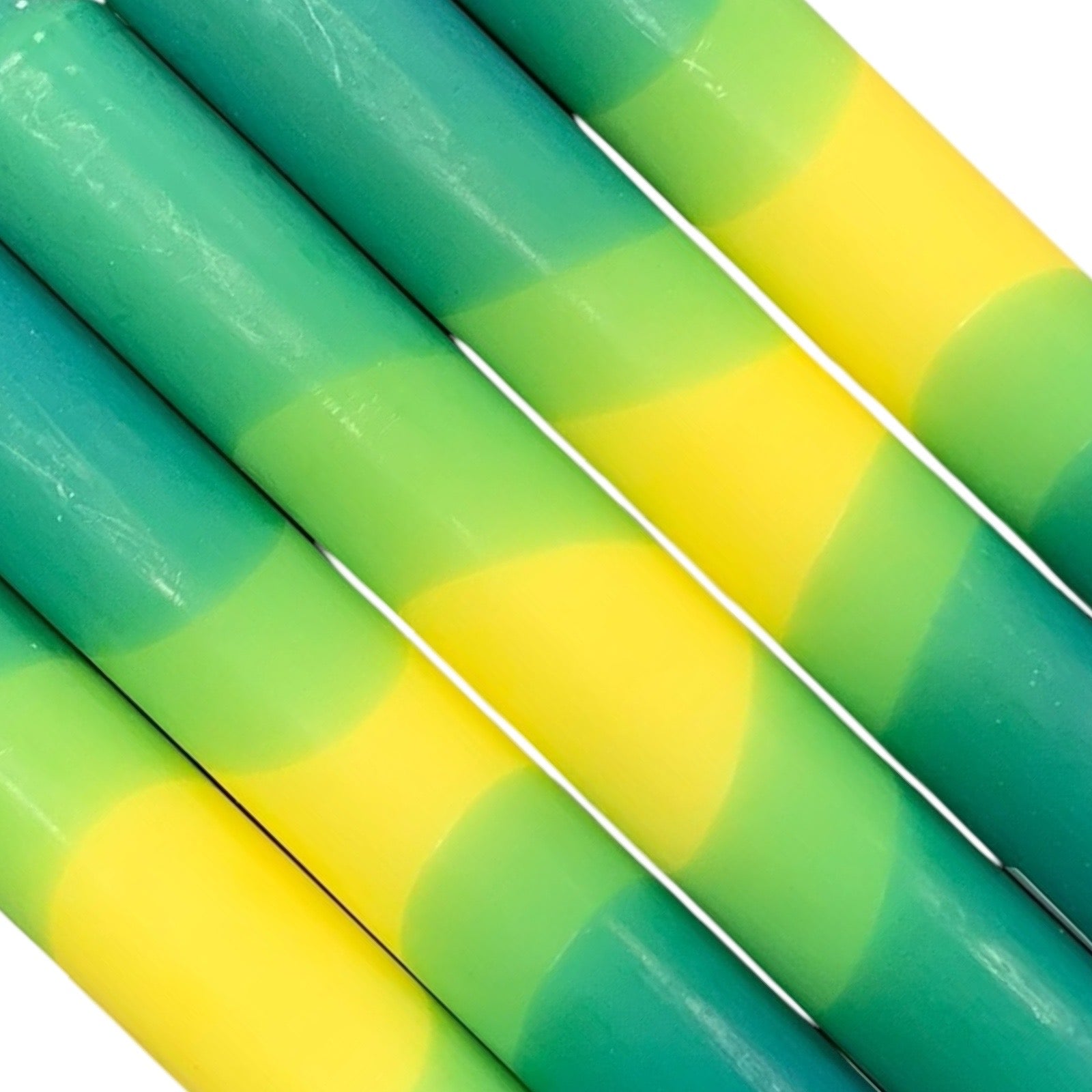 A row of 5 handmade dinner candles with a green base, a yellow centre, and a green top.