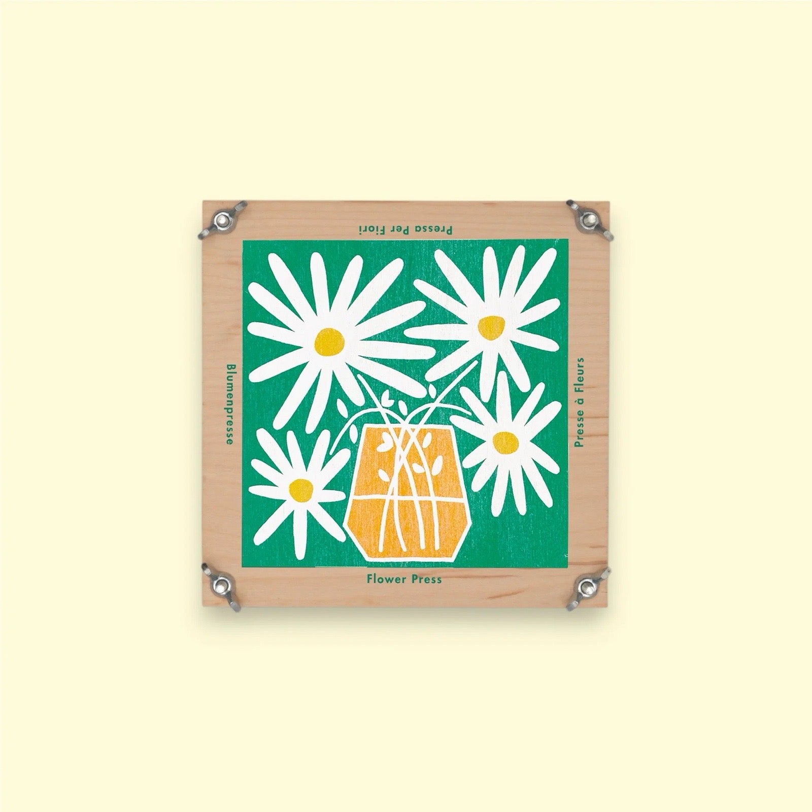 Square wooden flower press with a floral design on a light yellow background.