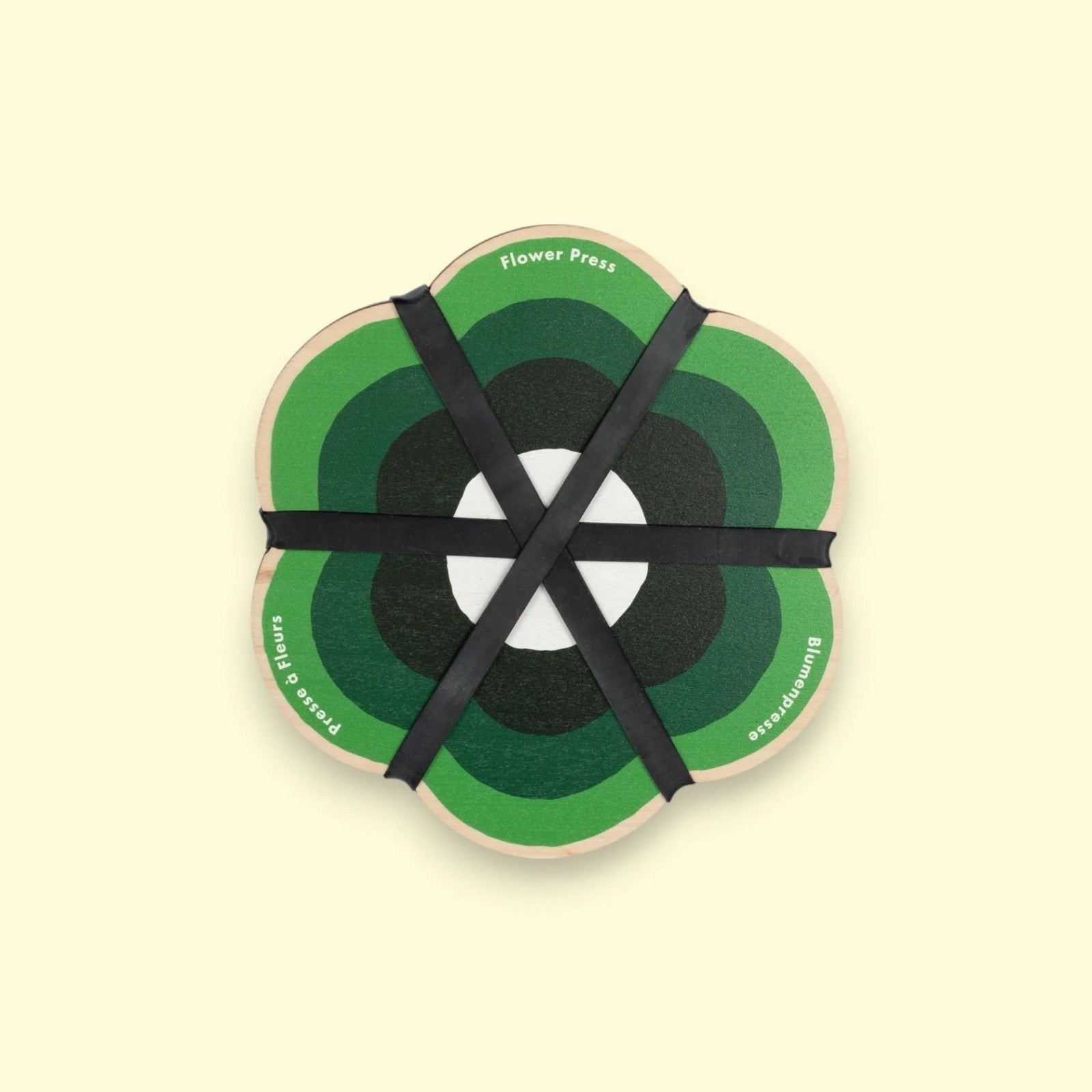 Round wooden flower press with green and black design on a beige background.