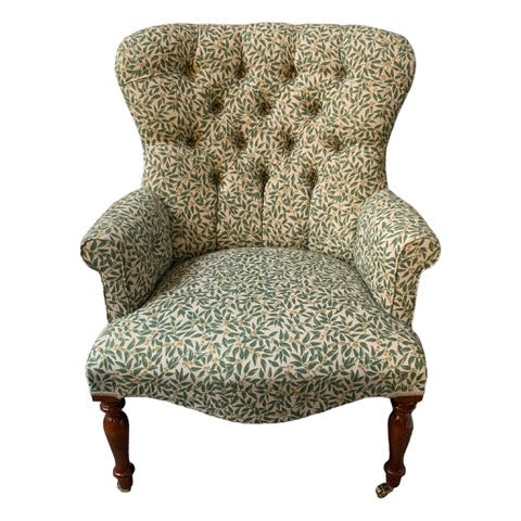A hand-crafted occasional armchair in a cream line fabric with green foliage and cream-coloured berries.