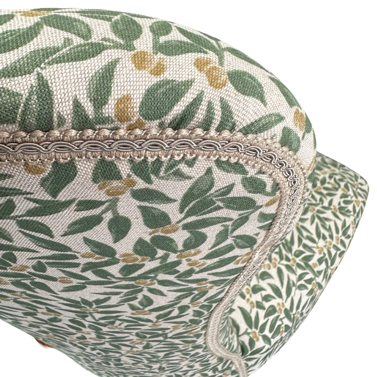 Close-up of a floral-patterned fabric with green leaves and beige flowers on a white background.