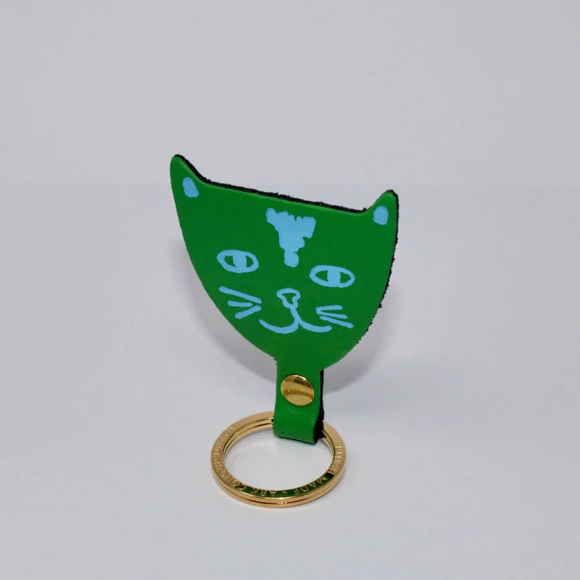 Green cat-shaped keyring with gold ring on a light grey background.