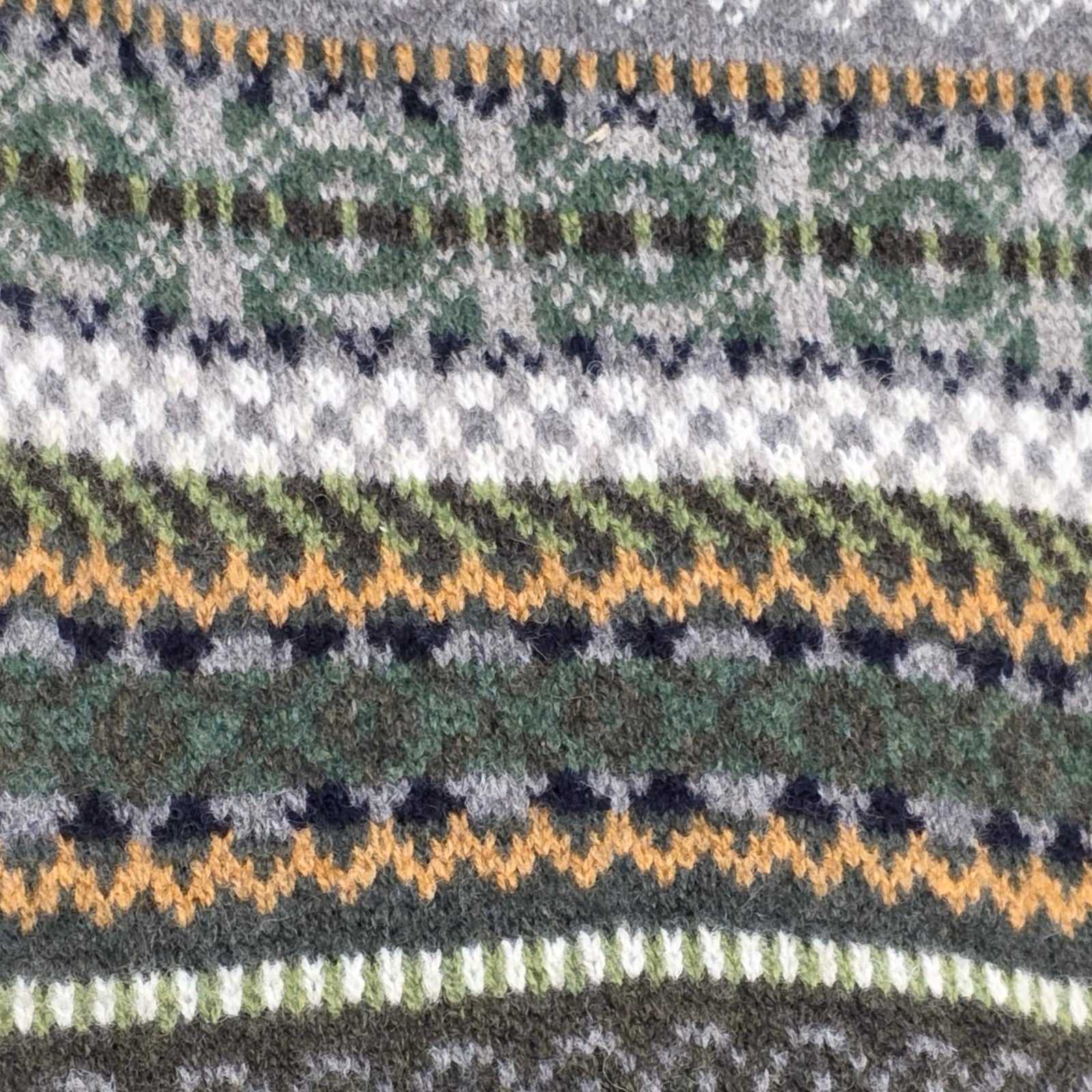 Close-up of a patterned fabric with green, black, and yellow stripes.