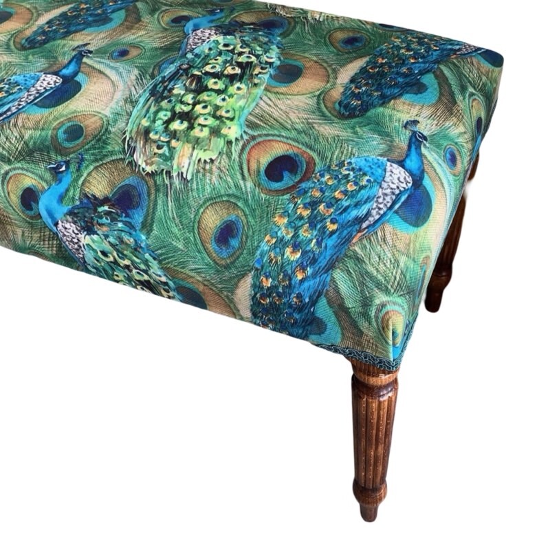 A rectangular green velvet bench with blue peacock patterns, green binding, and mahogany legs.