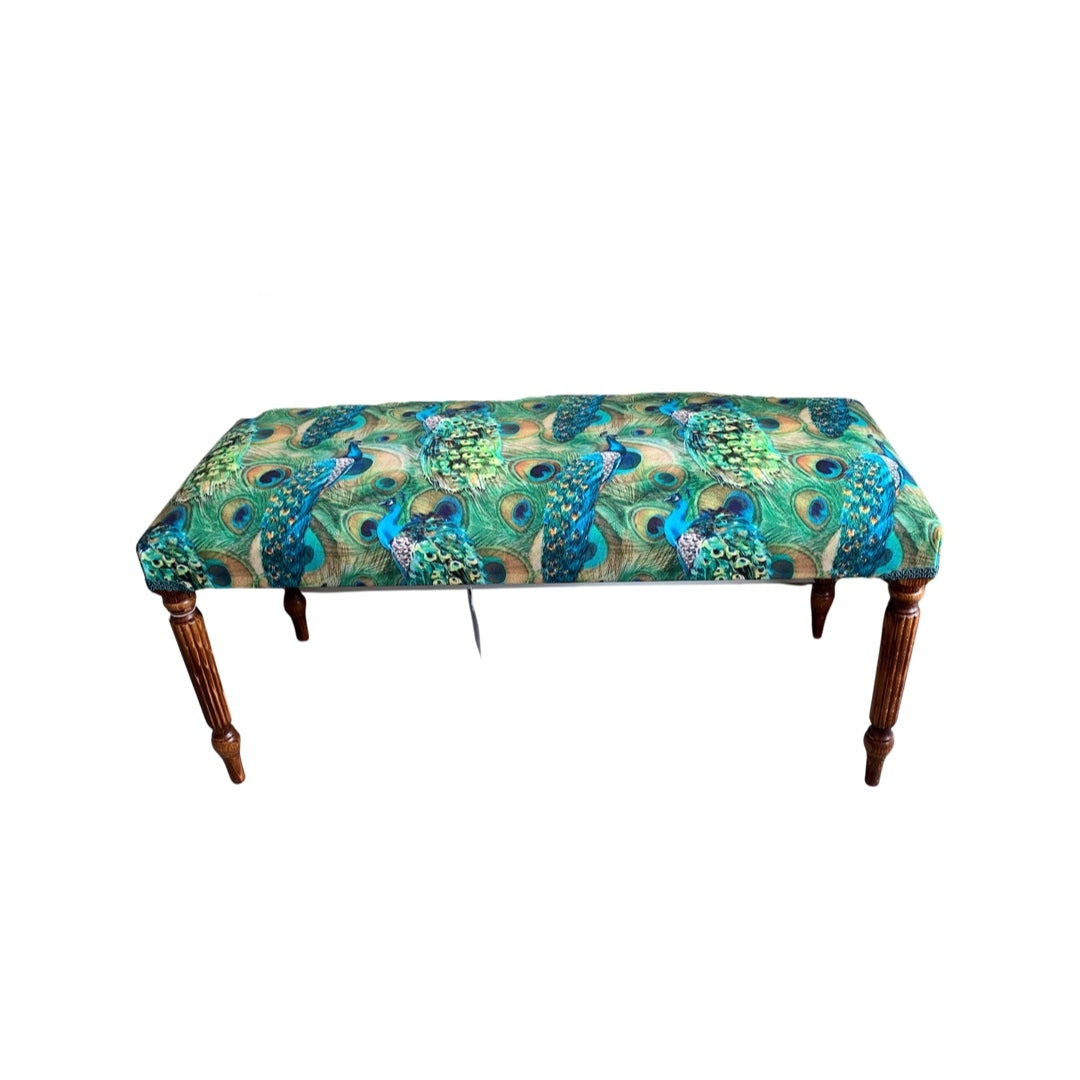 A rectangular green velvet bench with blue peacock patterns, green binding, and mahogany legs.