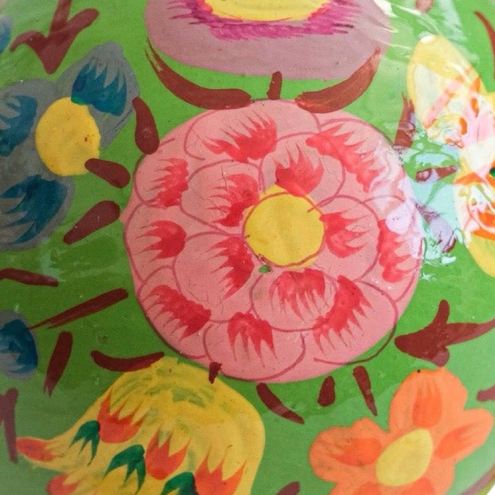 Colourful floral pattern bauble on a green background.
